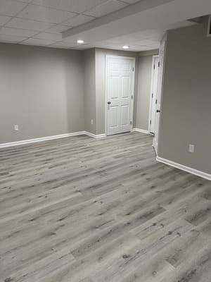 An empty basement with hardwood floors and gray walls.