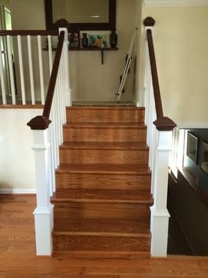 A wooden staircase with a white railing in a living room.