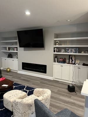 A living room with a fireplace and a flat screen tv on the wall.