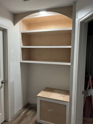 A hallway with shelves and a bench in it.
