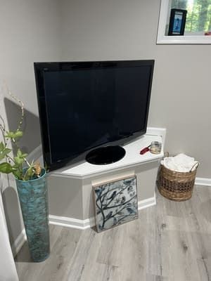 A flat screen tv is sitting on a corner shelf in a living room.