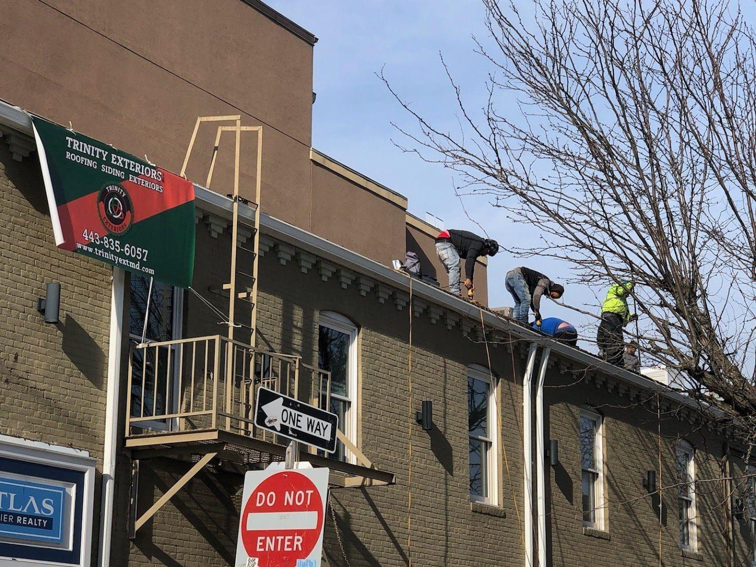 Workers on the side of the roof of a commercial building