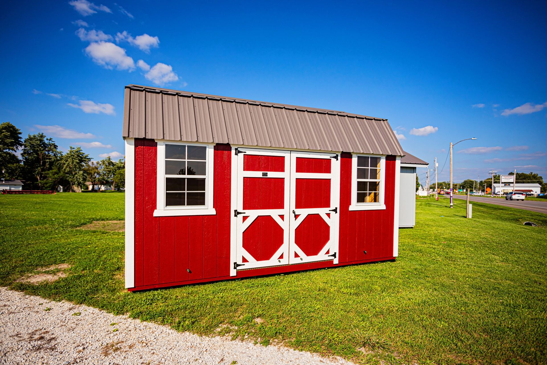 A small red barn is sitting in the middle of a grassy field.