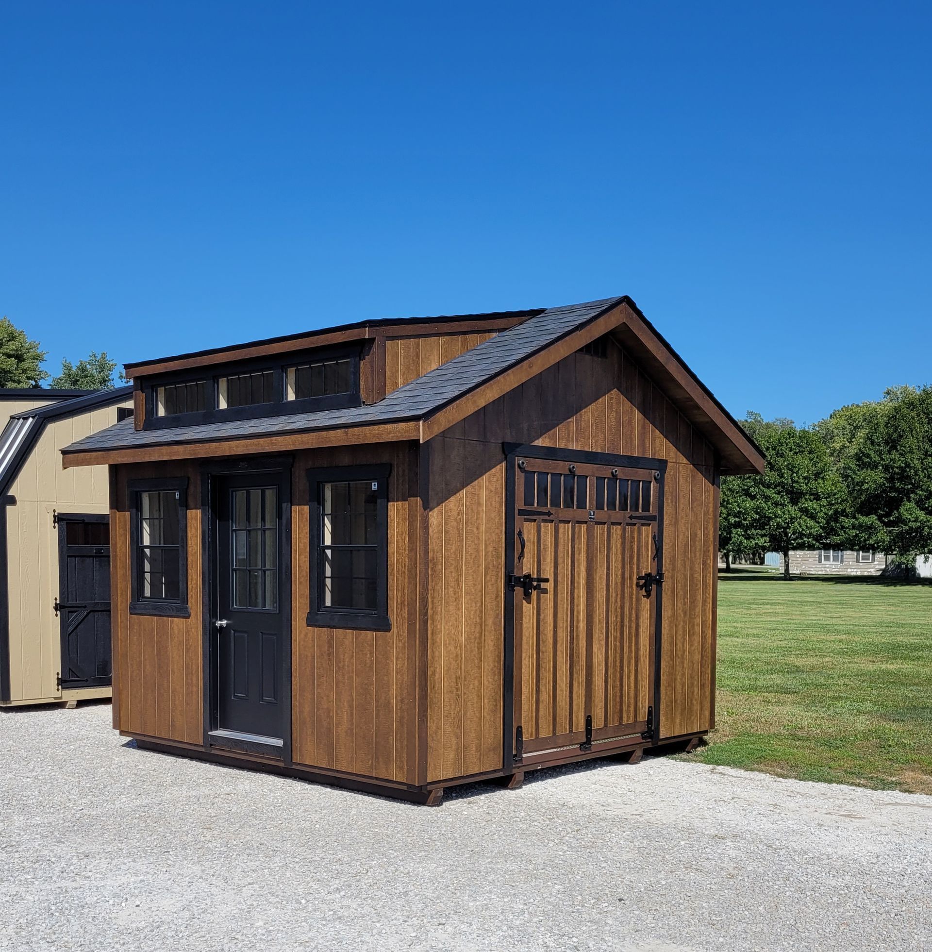 A small wooden shed in a gravel driveway