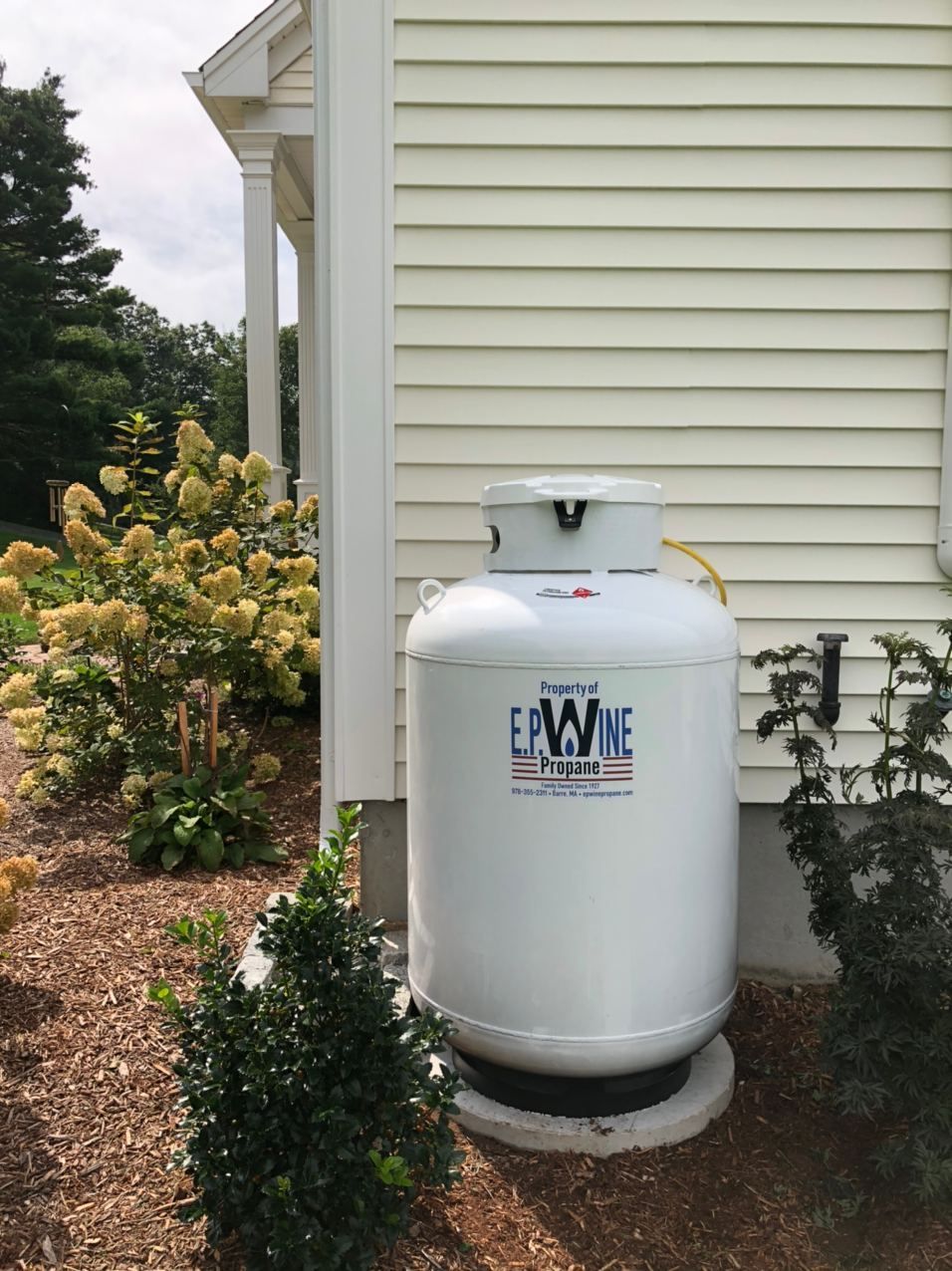 White propane tank outside a house.
