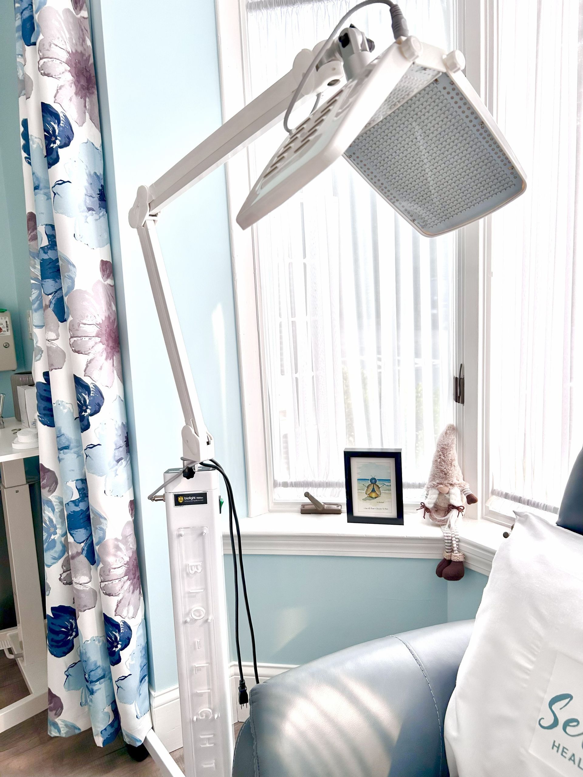 Floor lamp with a large, rectangular light panel in front of a window.