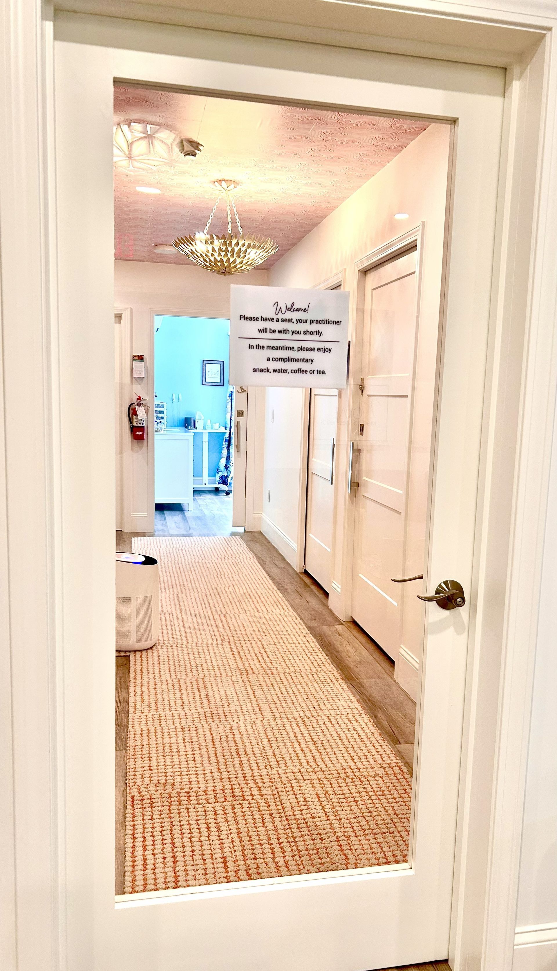 Hallway view from a doorway, peach rug, white doors, sign on the wall.