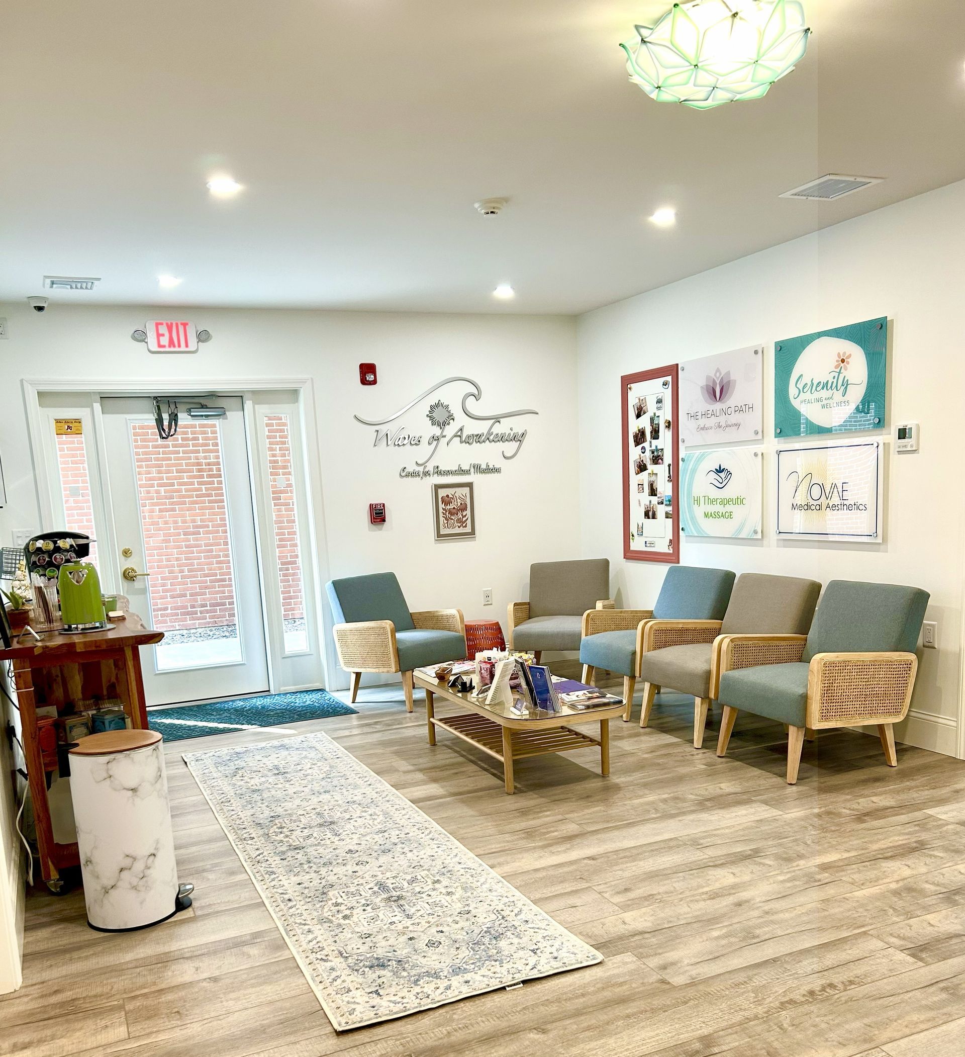 Waiting room with chairs, rug, coffee table, art, and exit sign.