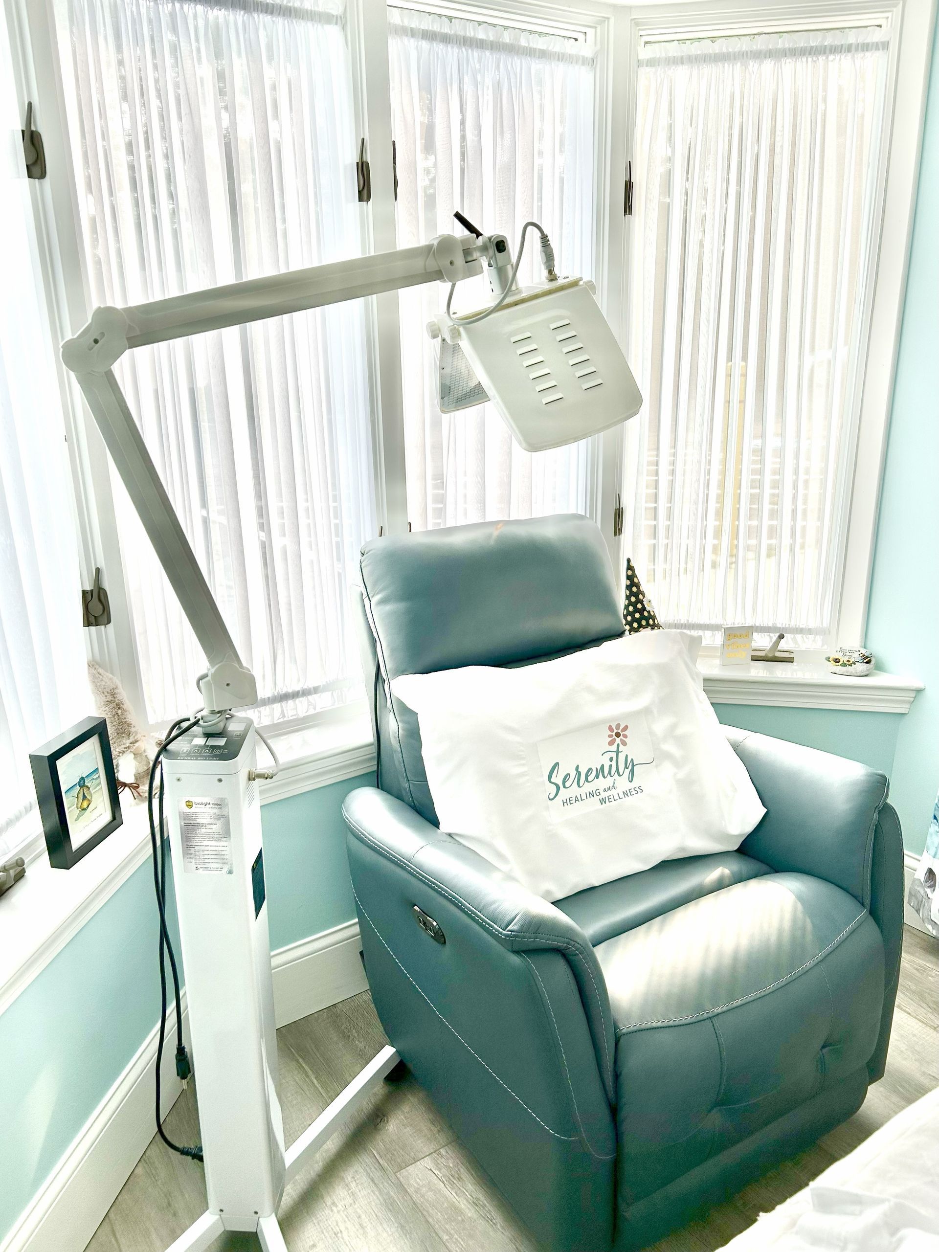 A light therapy machine next to a blue recliner chair with a pillow that reads