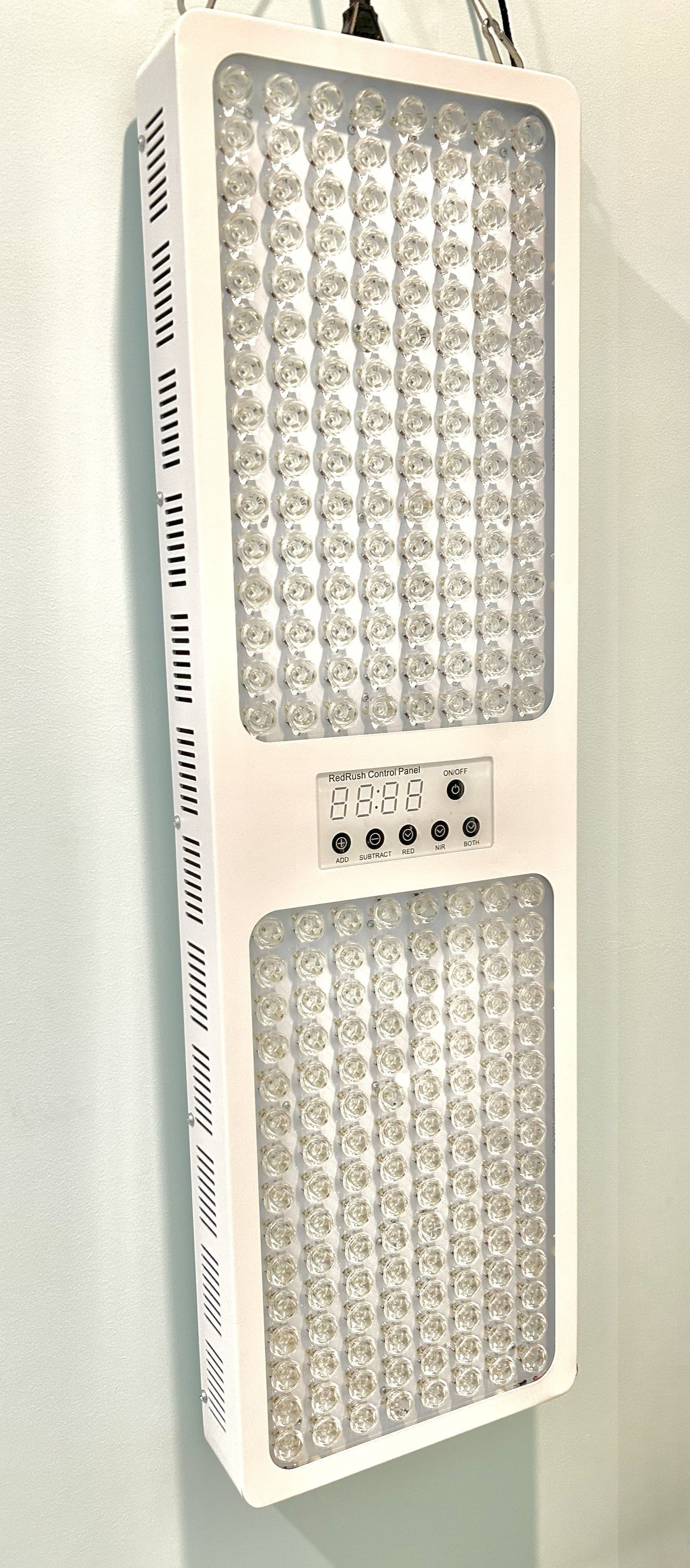 White LED light therapy panel with control panel hanging on a wall.