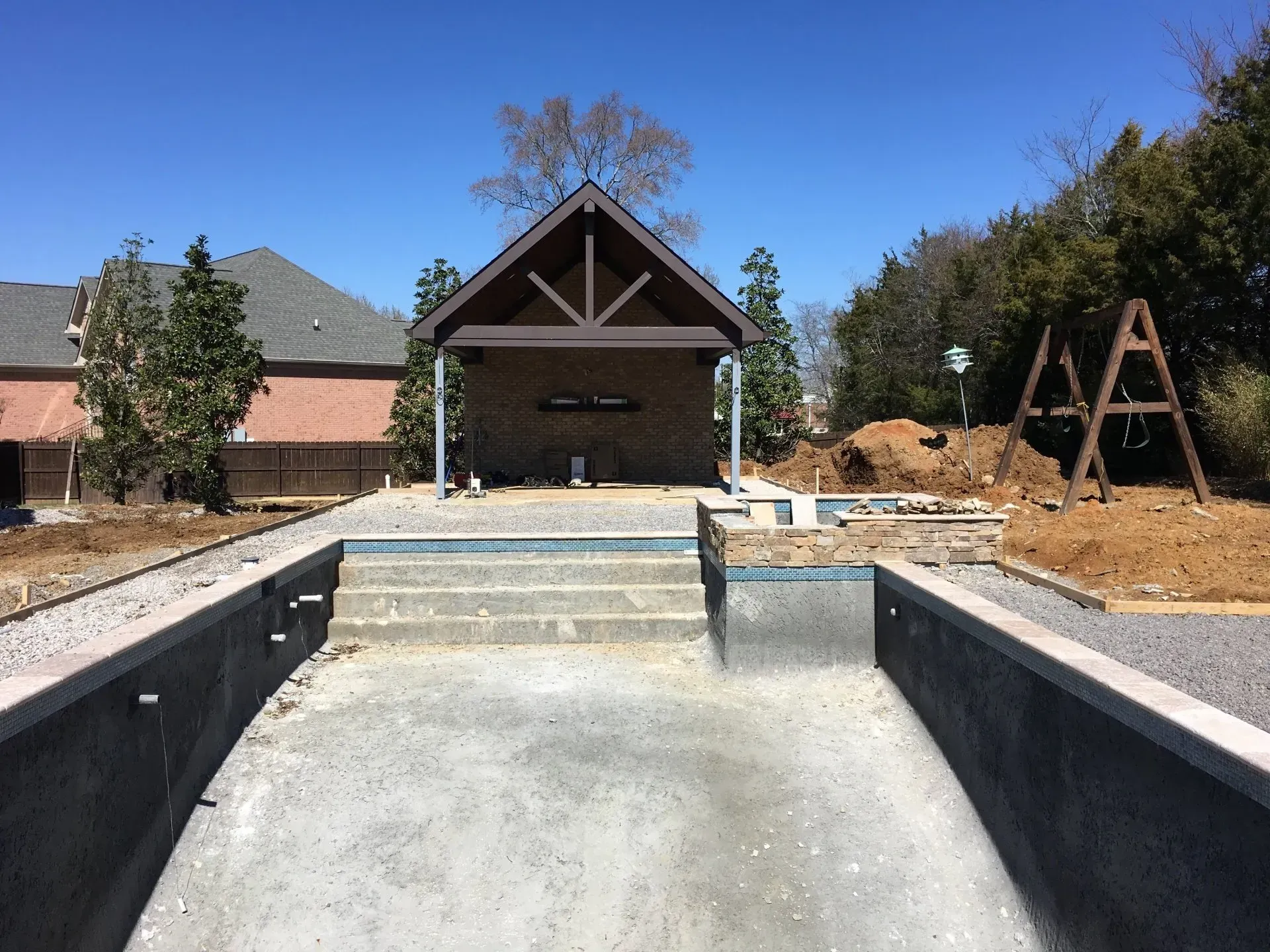 Empty pool under construction with a pavilion in the background on a sunny day.