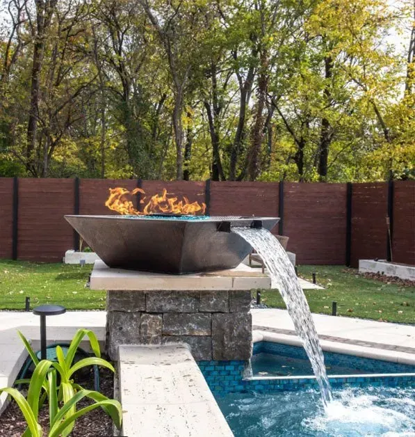 Fire and water feature next to a pool. Bronze bowl with flames and waterfall spilling into the pool.