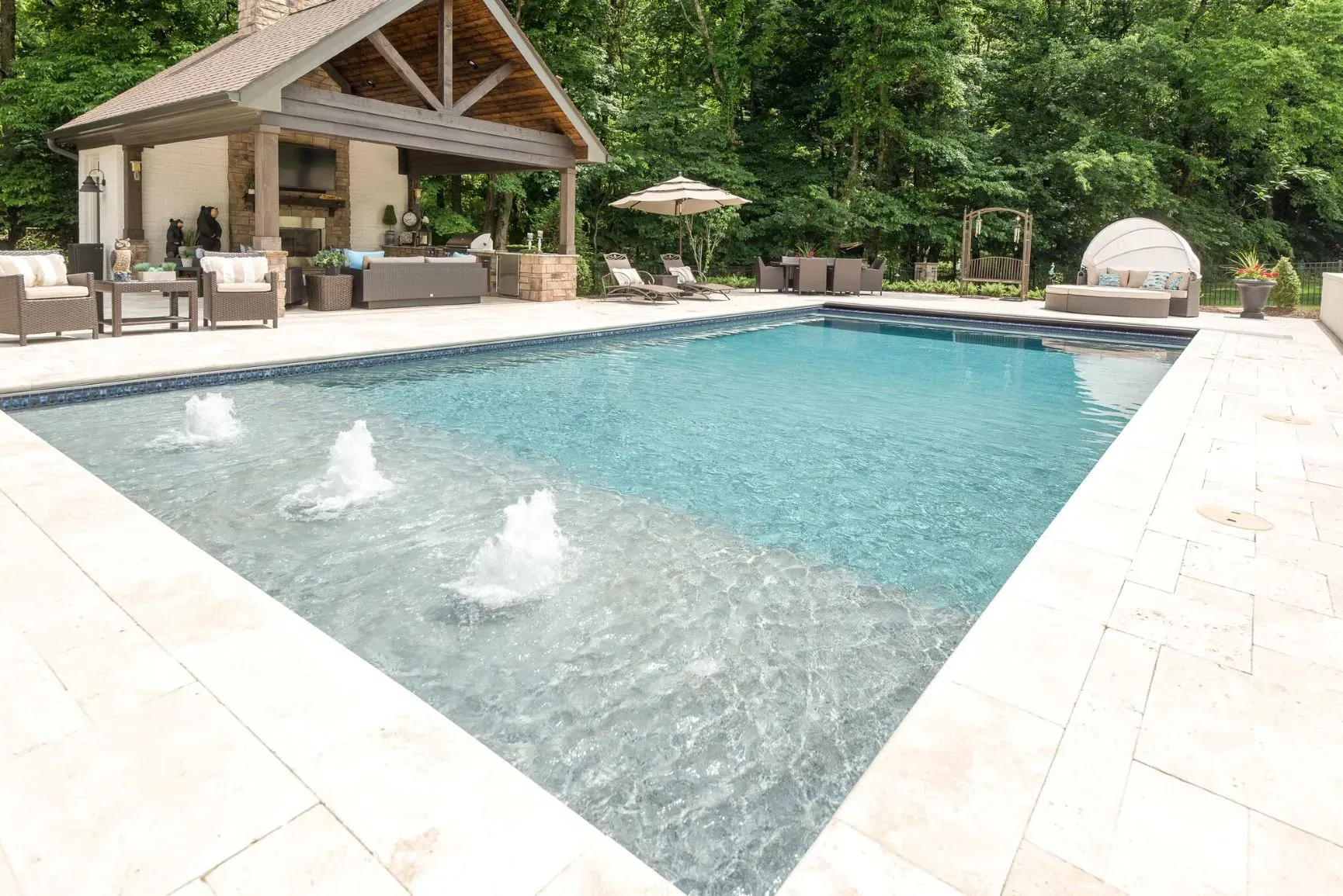 Swimming pool with water fountains, patio, and outdoor living area.