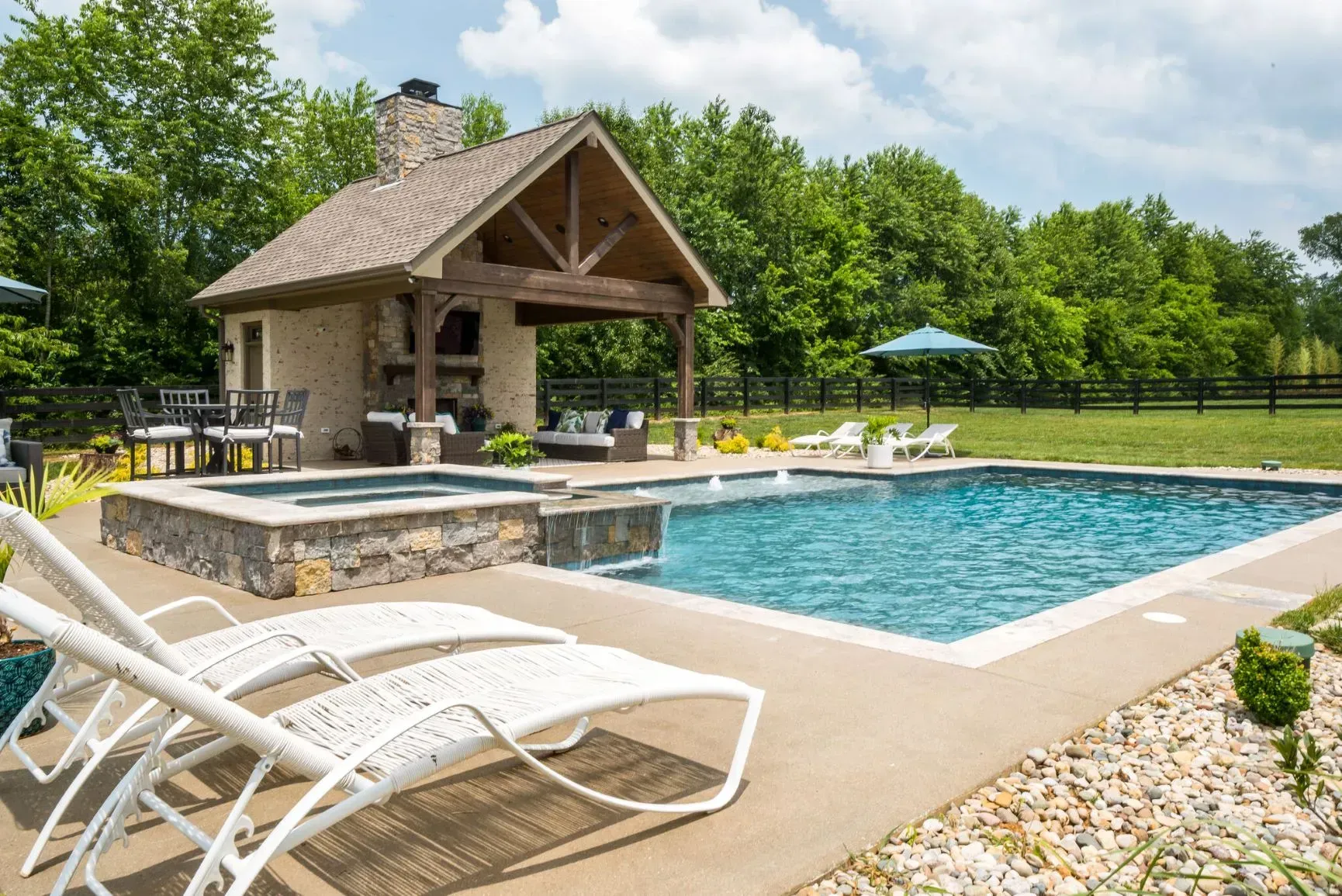 Pool area with a gazebo, pool, and lounge chairs.