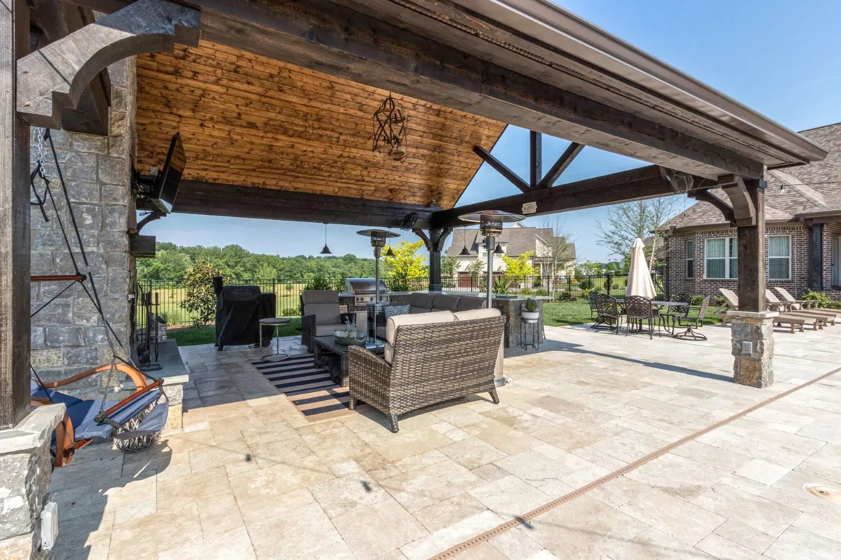Patio with wood pergola, stone fireplace, and outdoor seating.
