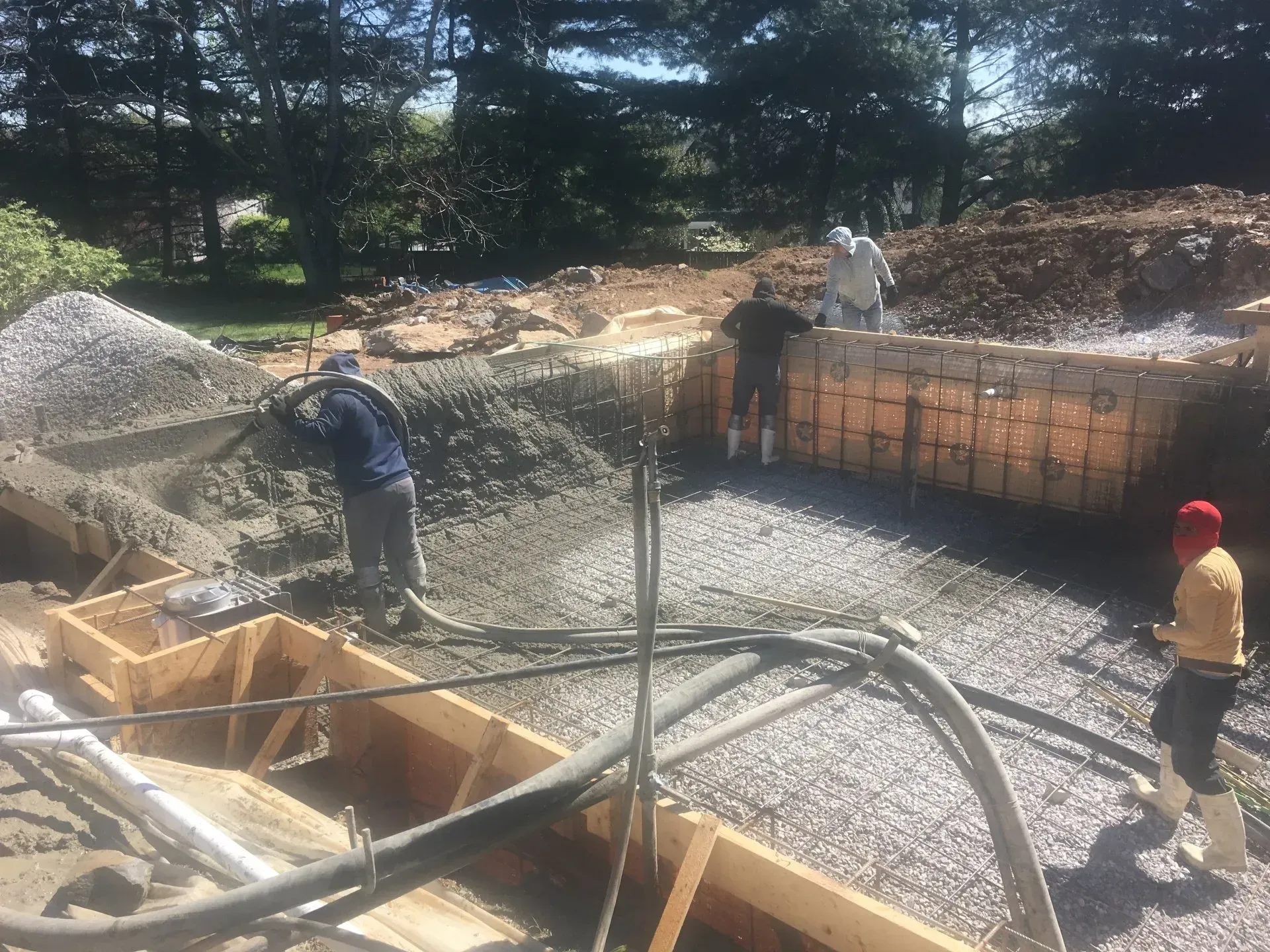 Construction workers pouring concrete into wooden forms.