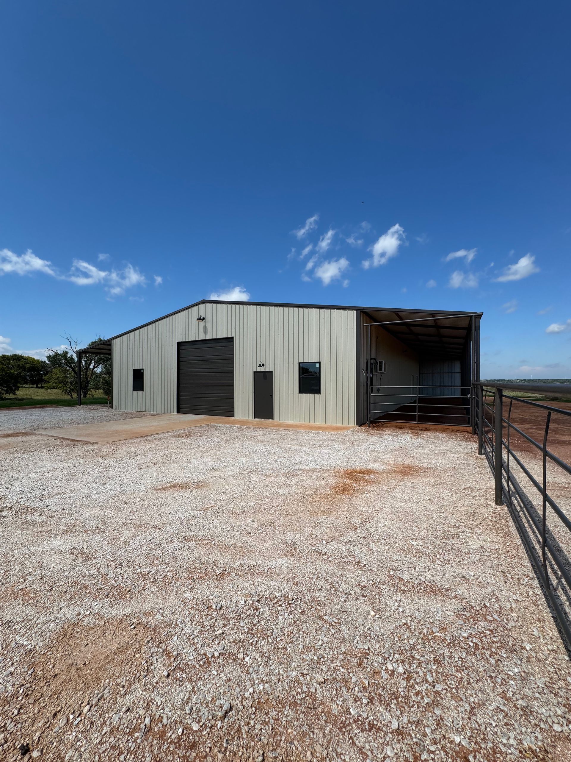 Metal barn with a gravel yard, under a blue sky.