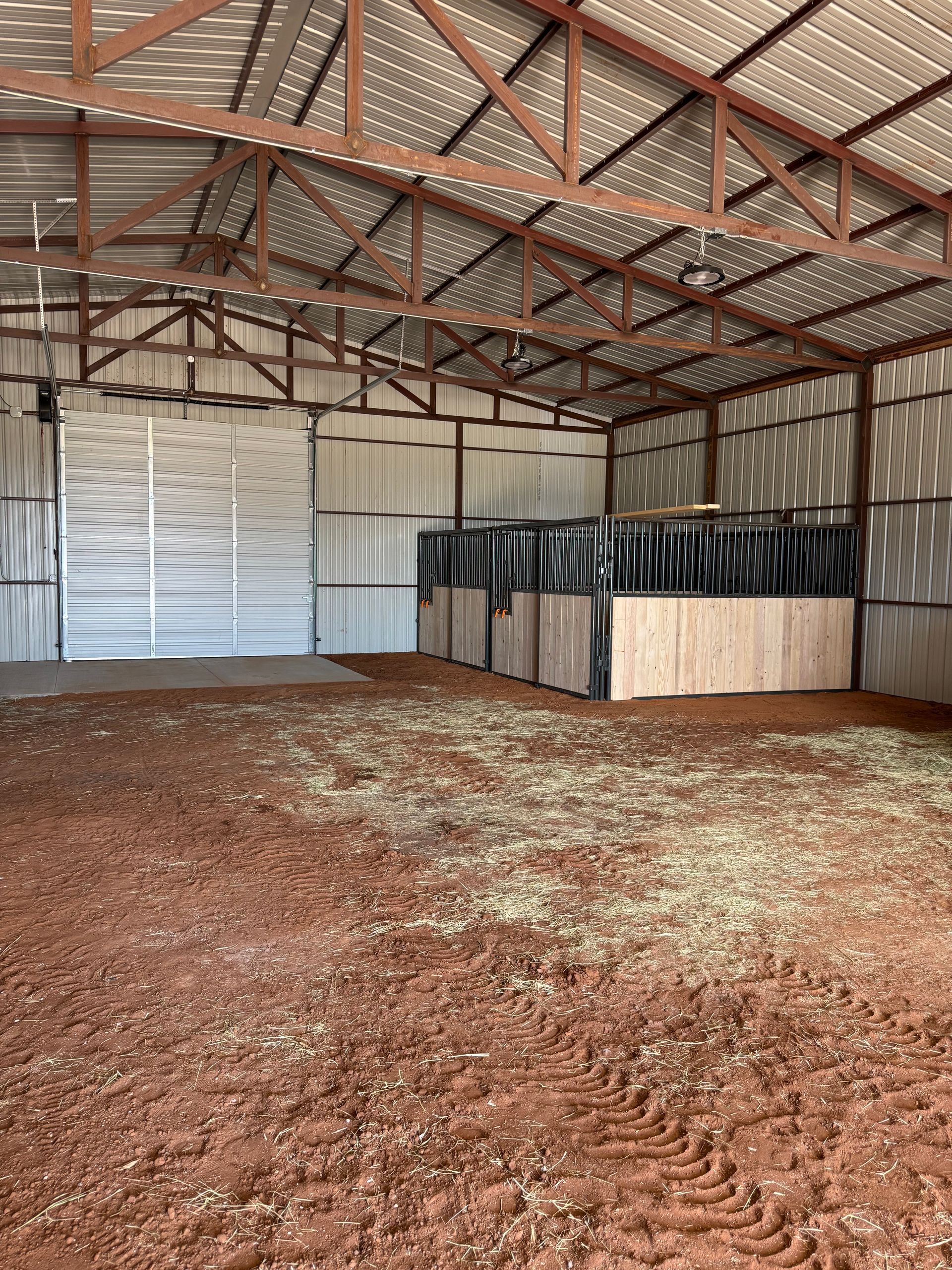 Interior of a barn with horse stalls and a dirt floor.