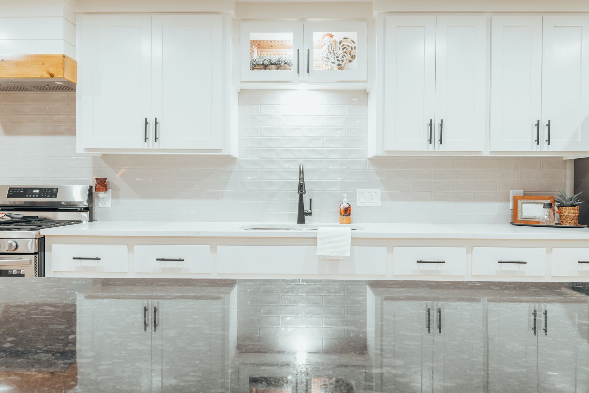 A kitchen with white cabinets, granite counter tops, a sink and a stove.