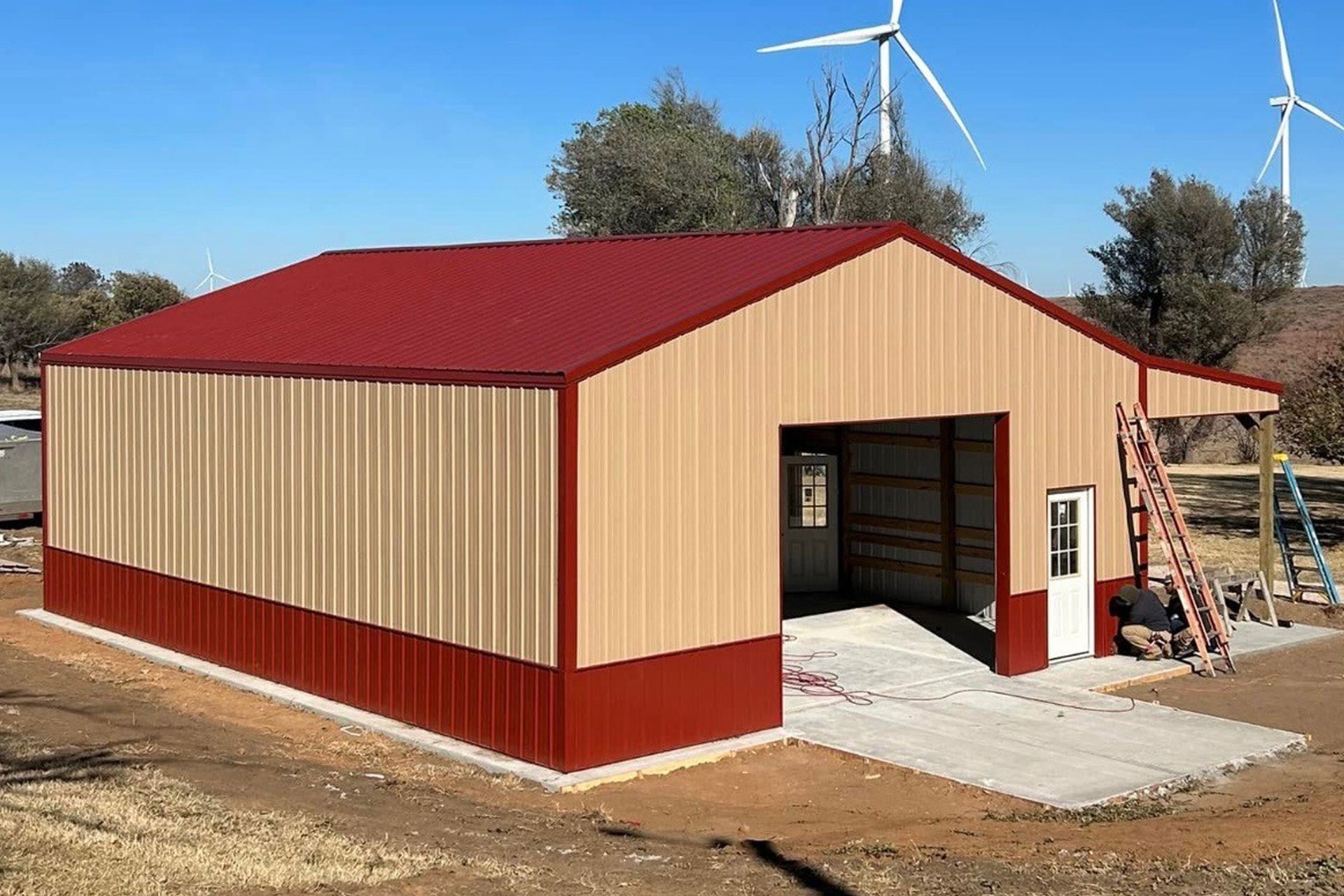 A large metal building with a red roof and a windmill in the background.