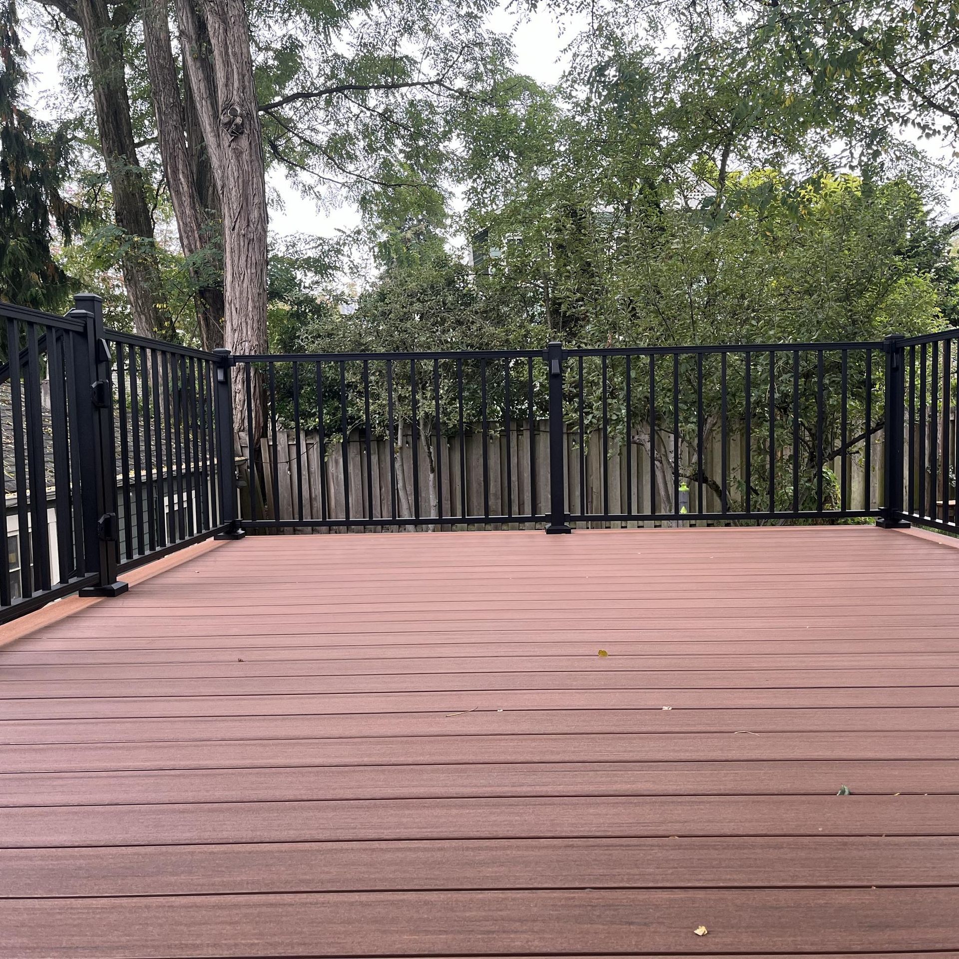 A wooden deck with black railing