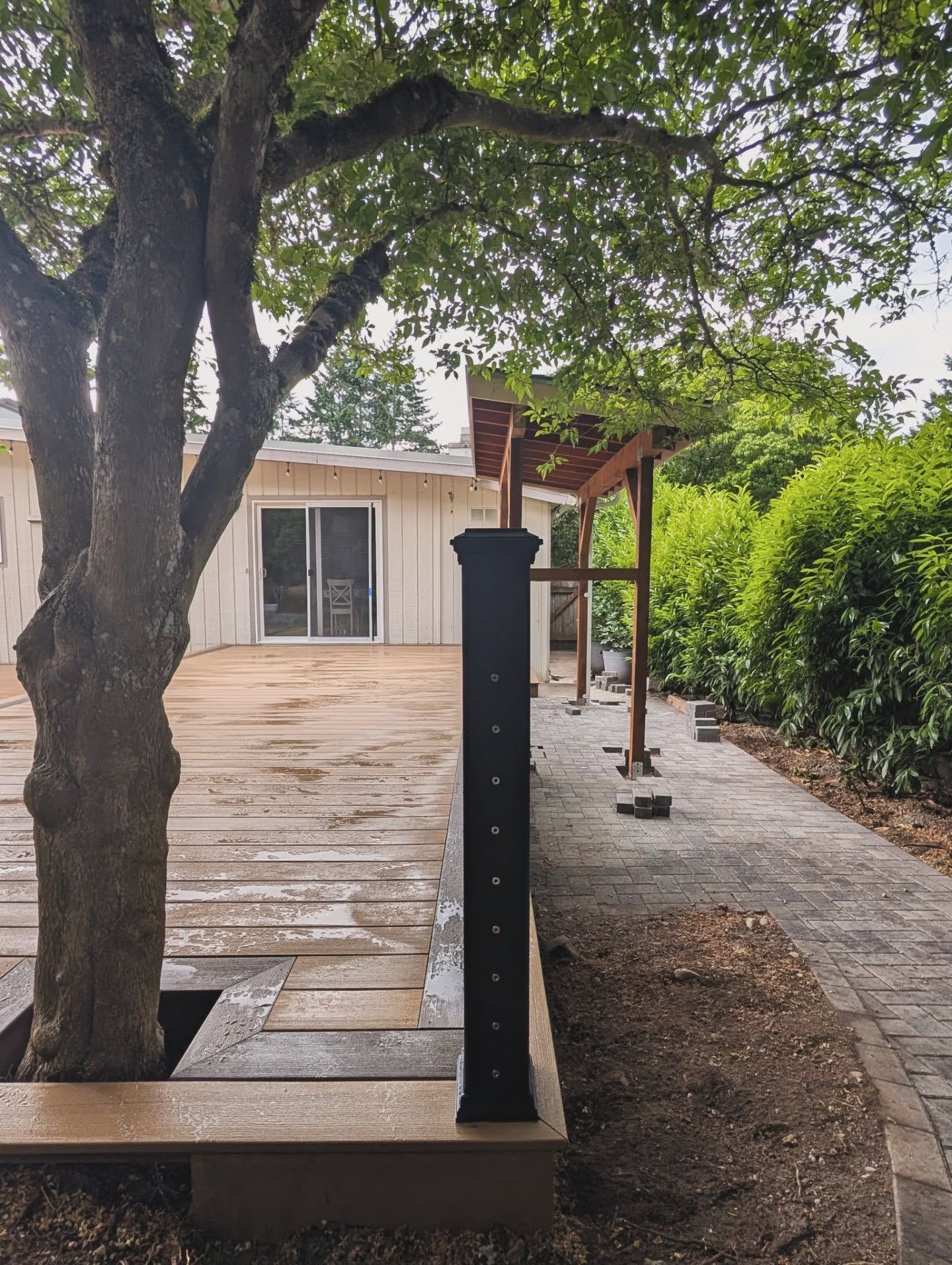 A wooden deck with white house and trees in the background.