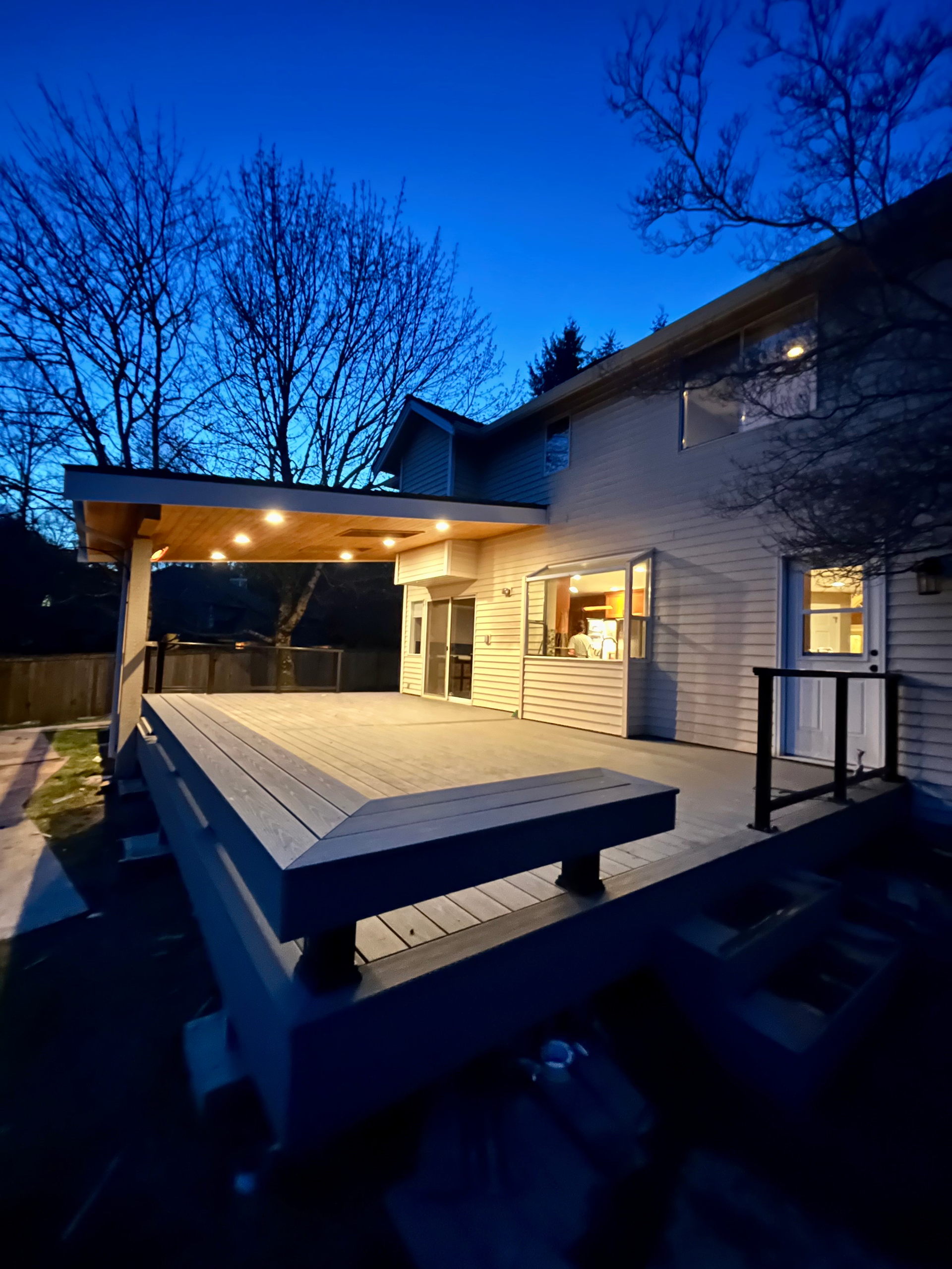 A house with a large deck in front of it at night