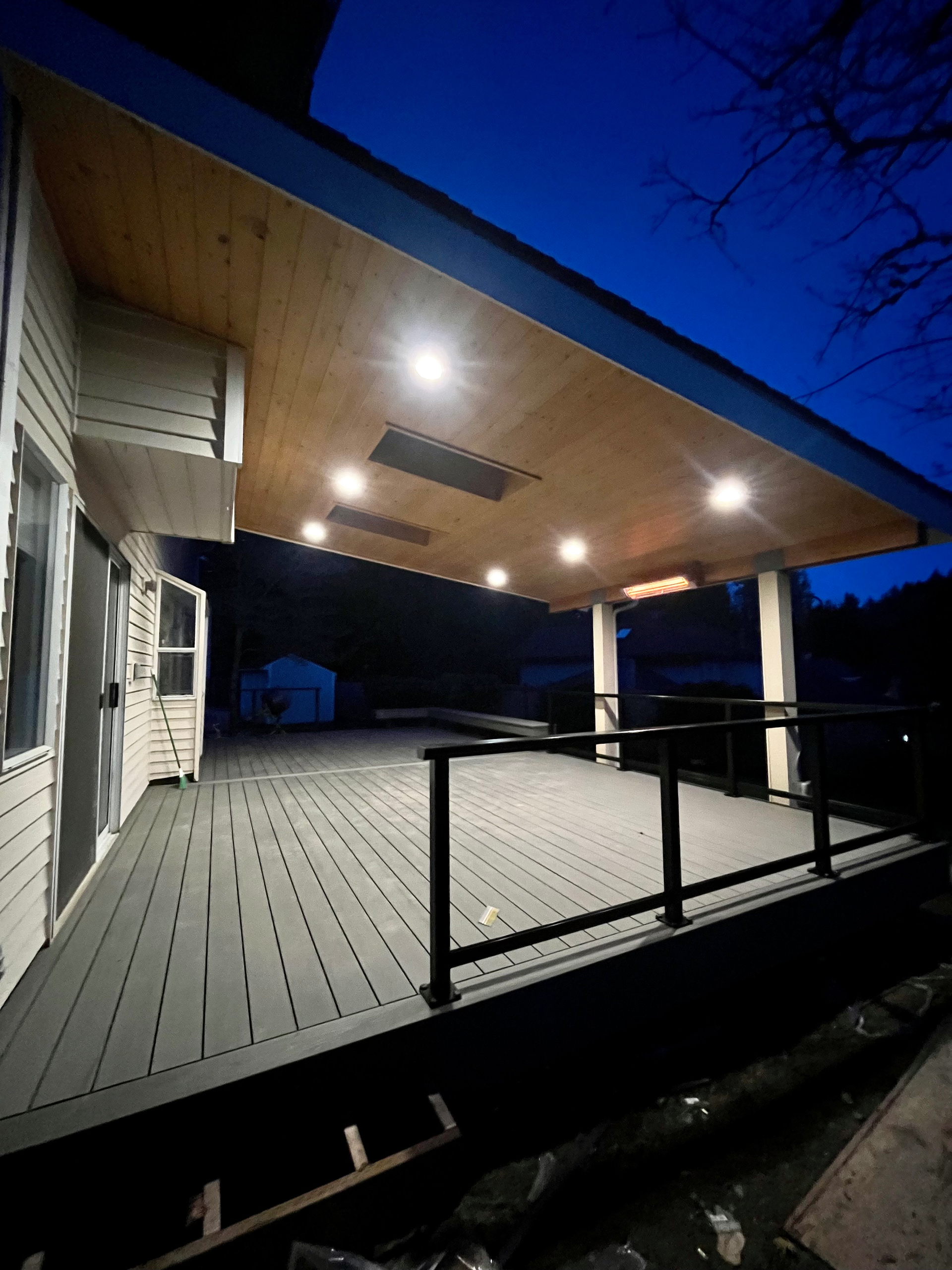 A large deck with a railing is lit up at night