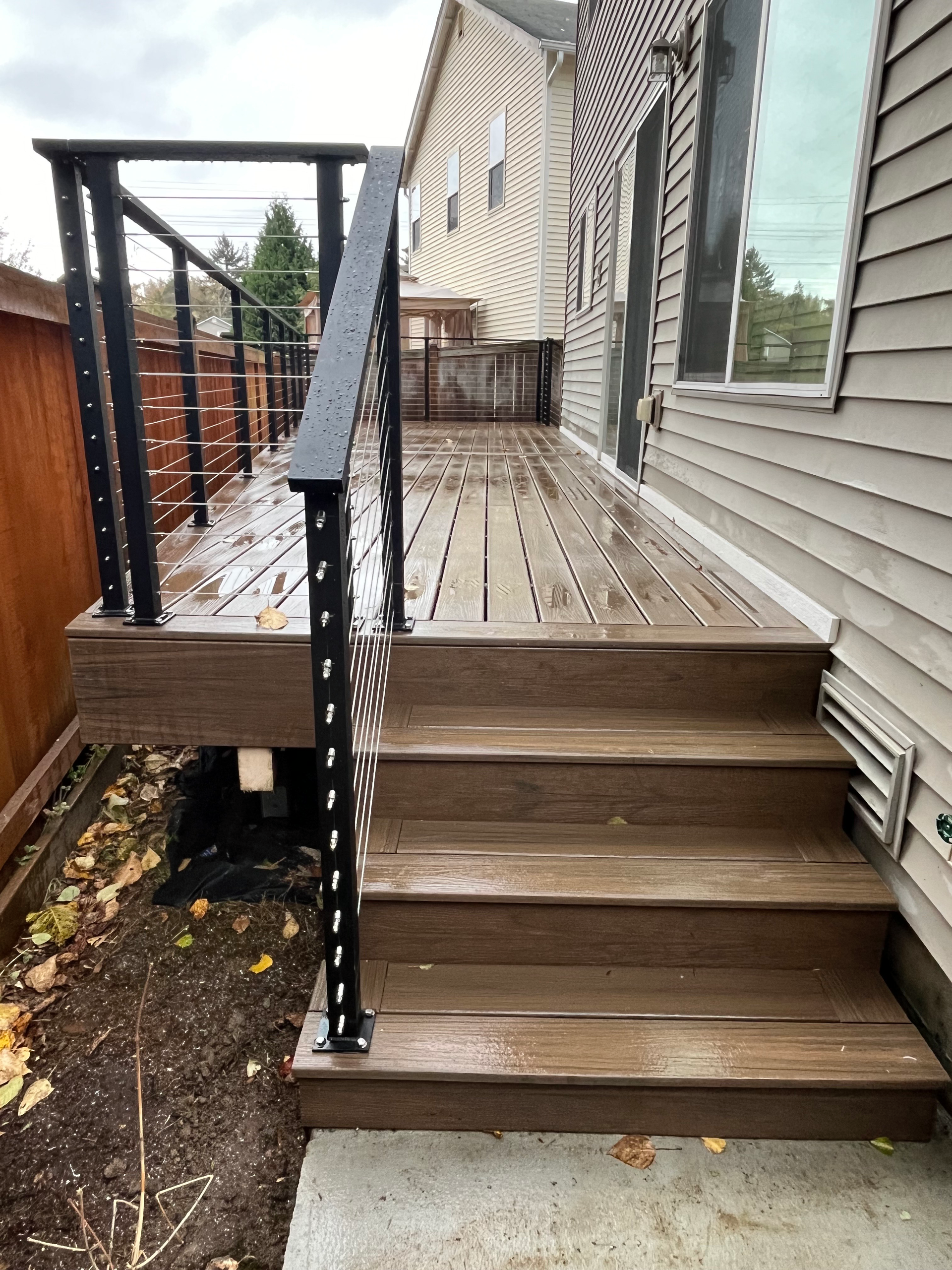 A wooden deck with stairs leading up to it next to a house.
