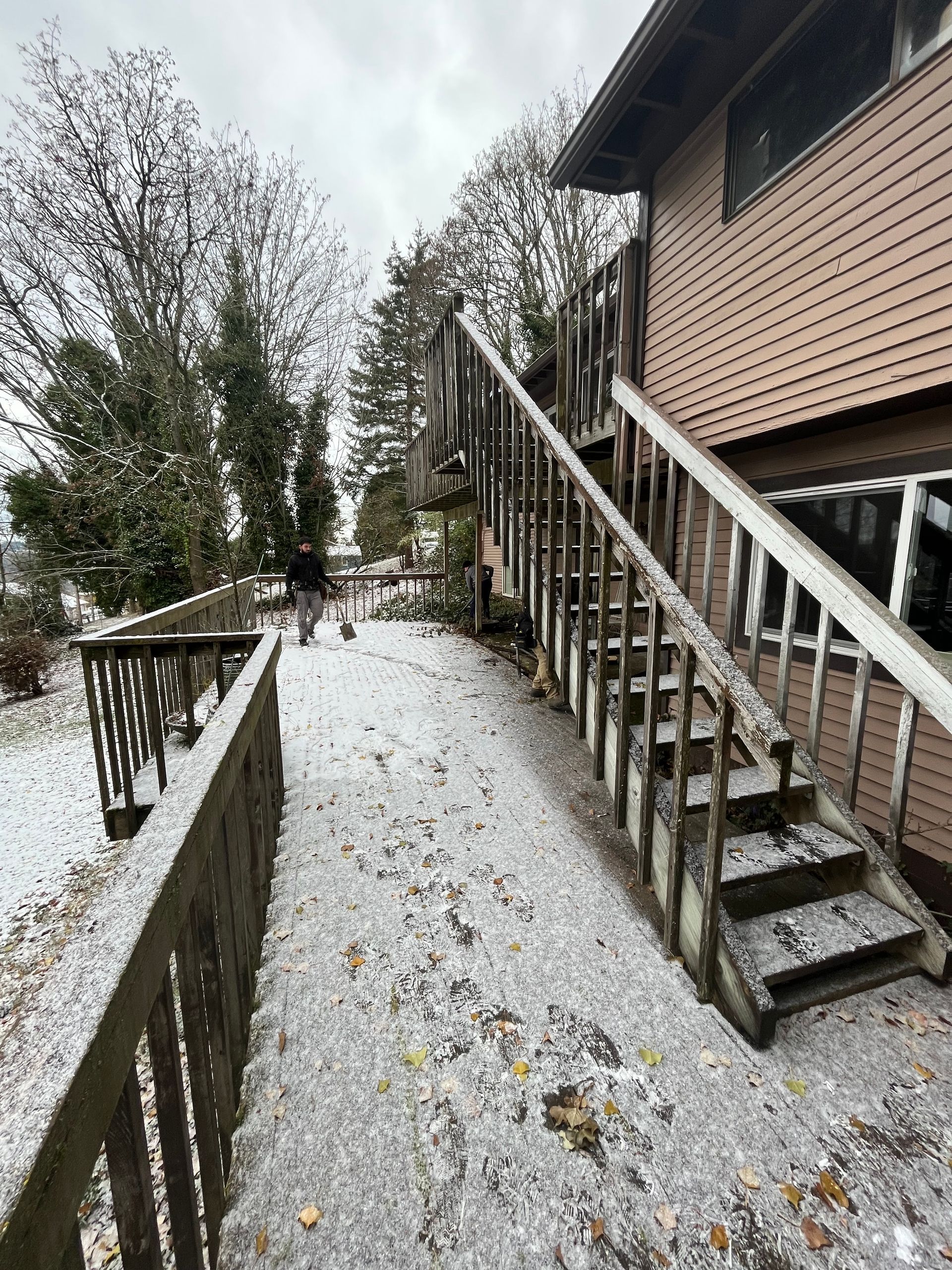 A wooden deck with stairs leading up to it is covered in snow.