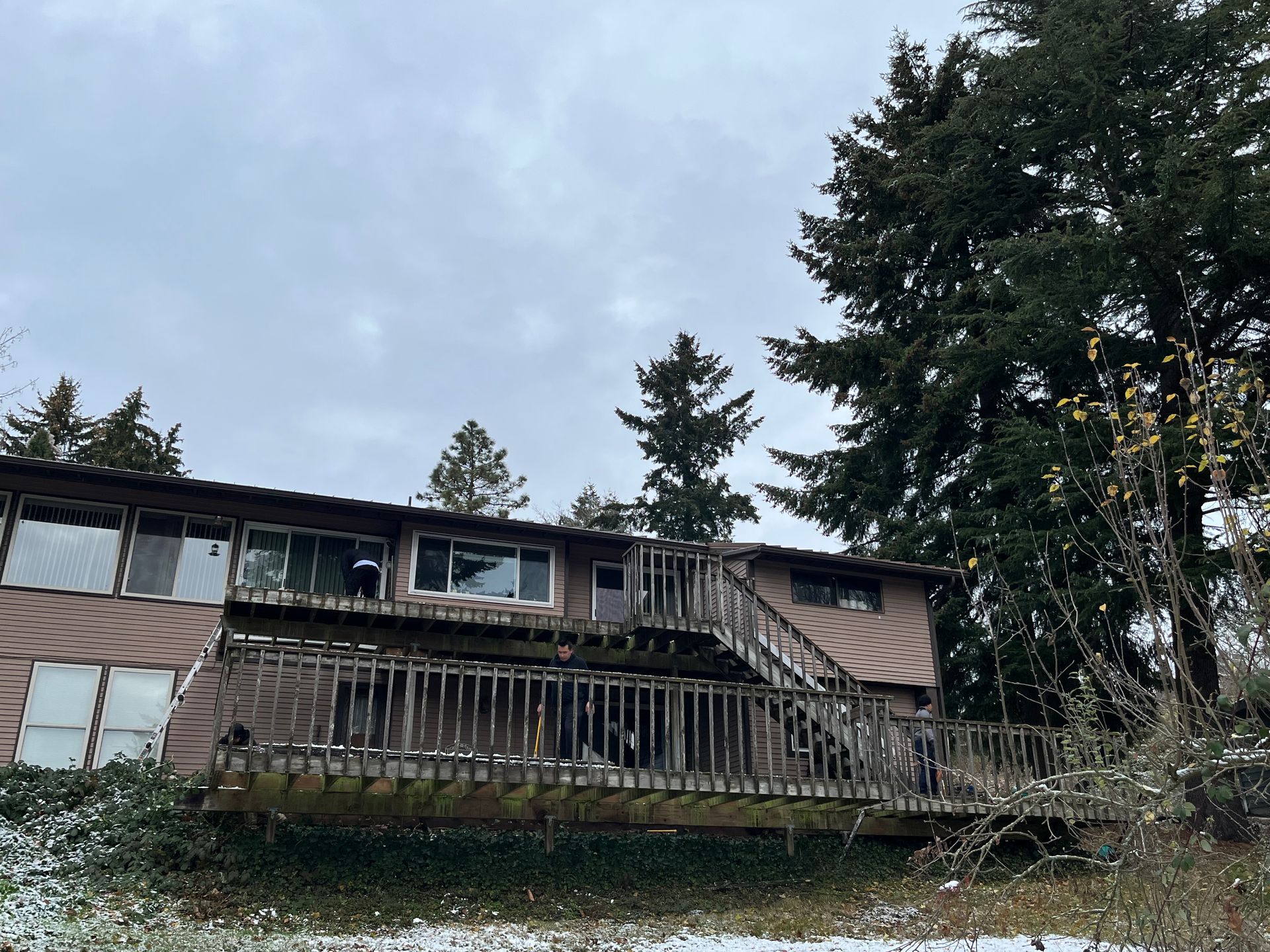 A house with a large deck and stairs surrounded by trees