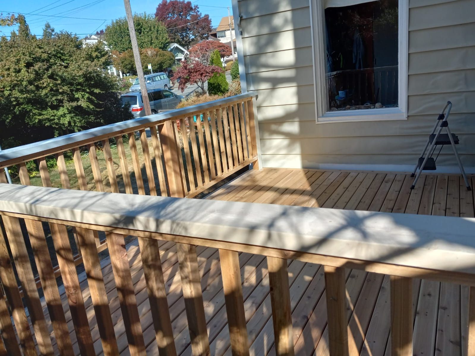 A wooden deck with a railing on the side of a house.