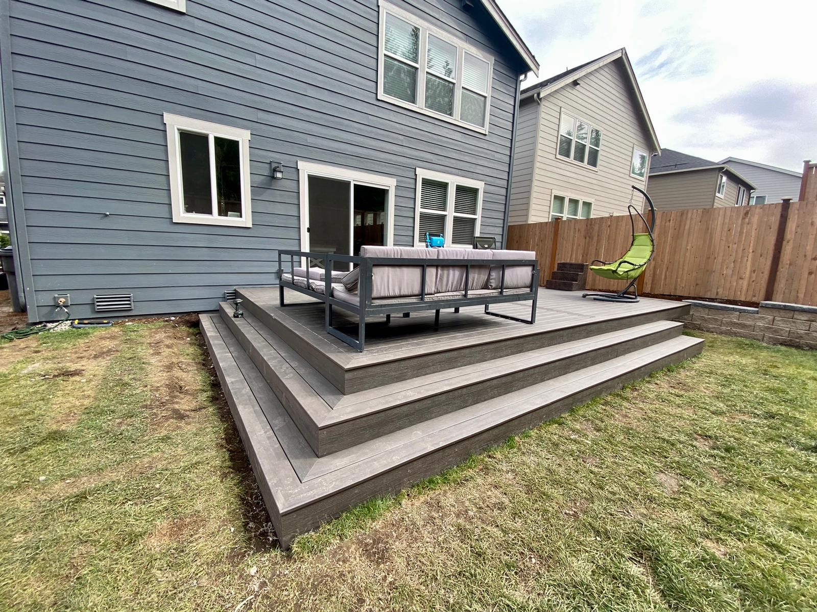 A patio with a couch and chairs in front of a house.