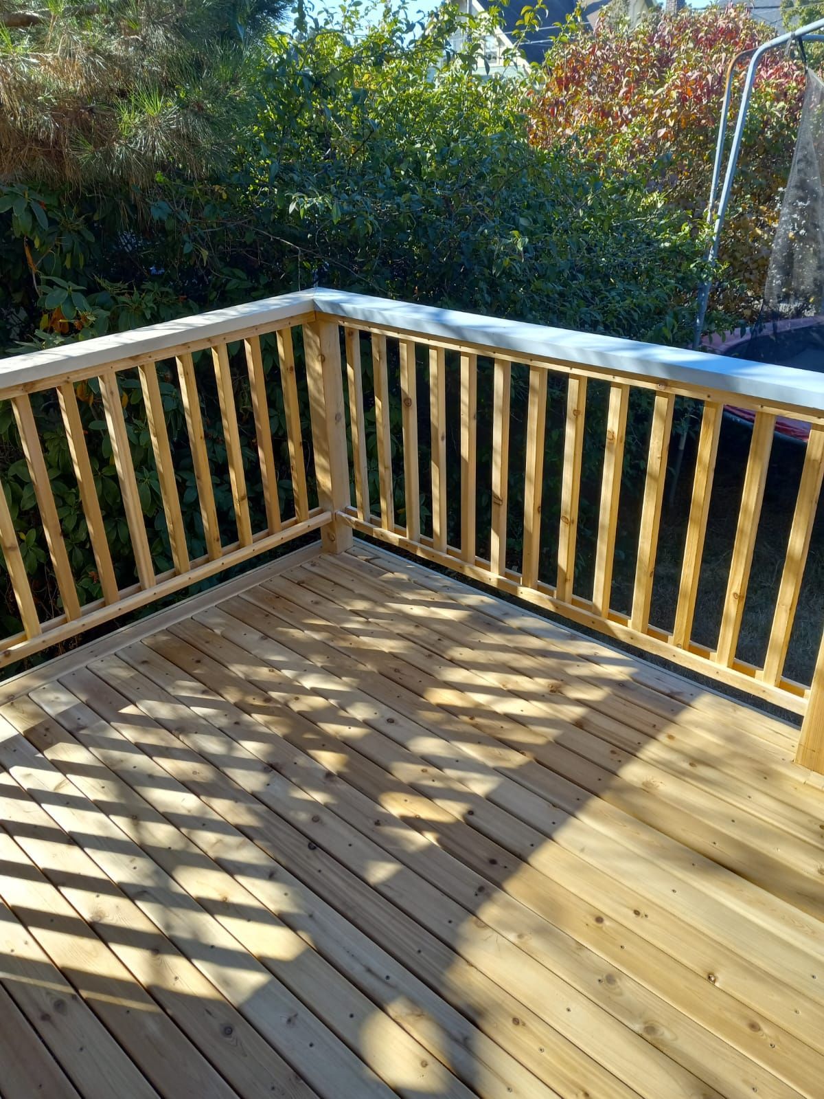 A wooden deck with a wooden railing and trees in the background.