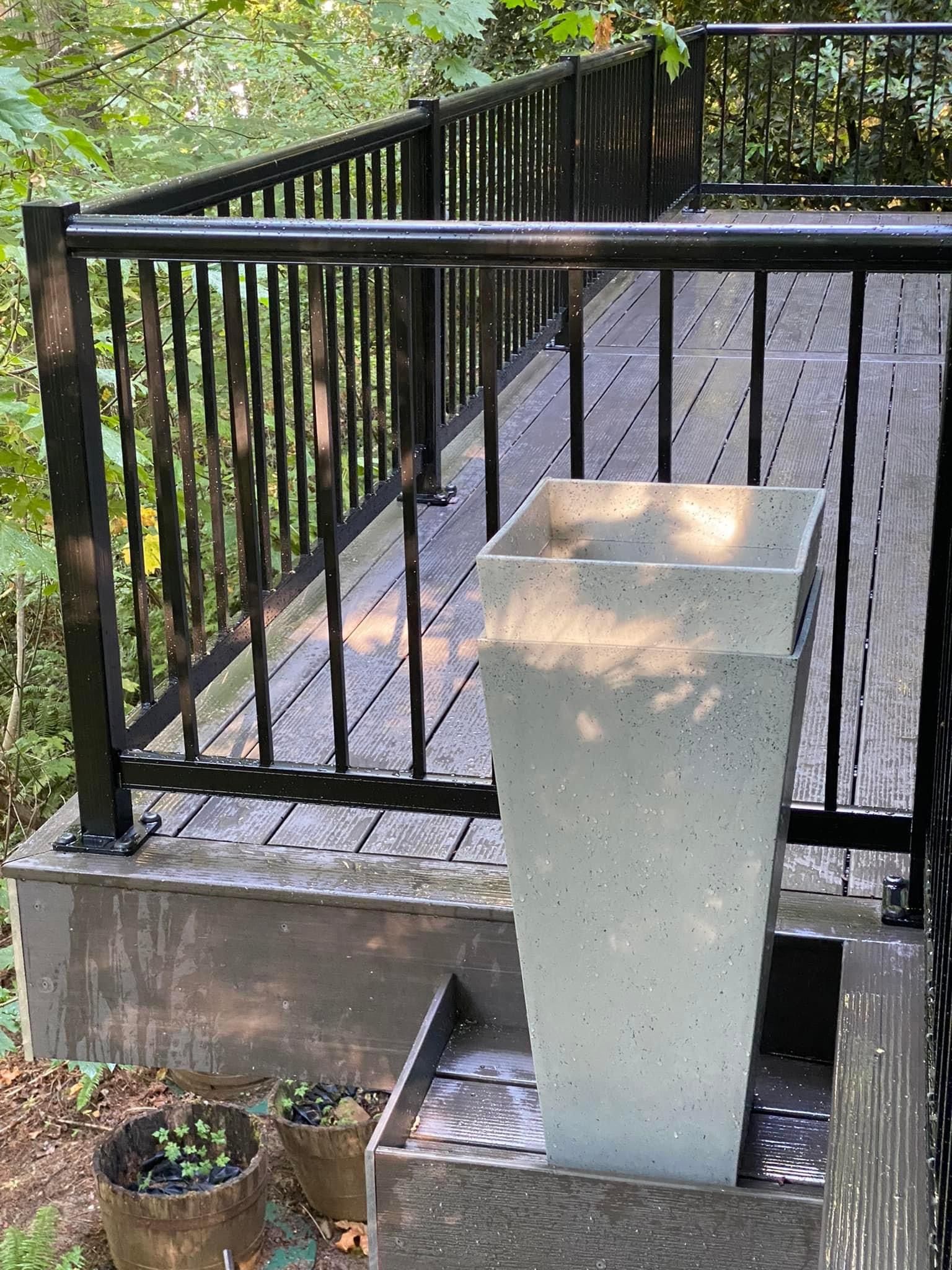 A planter is sitting on top of a wooden deck next to a railing.