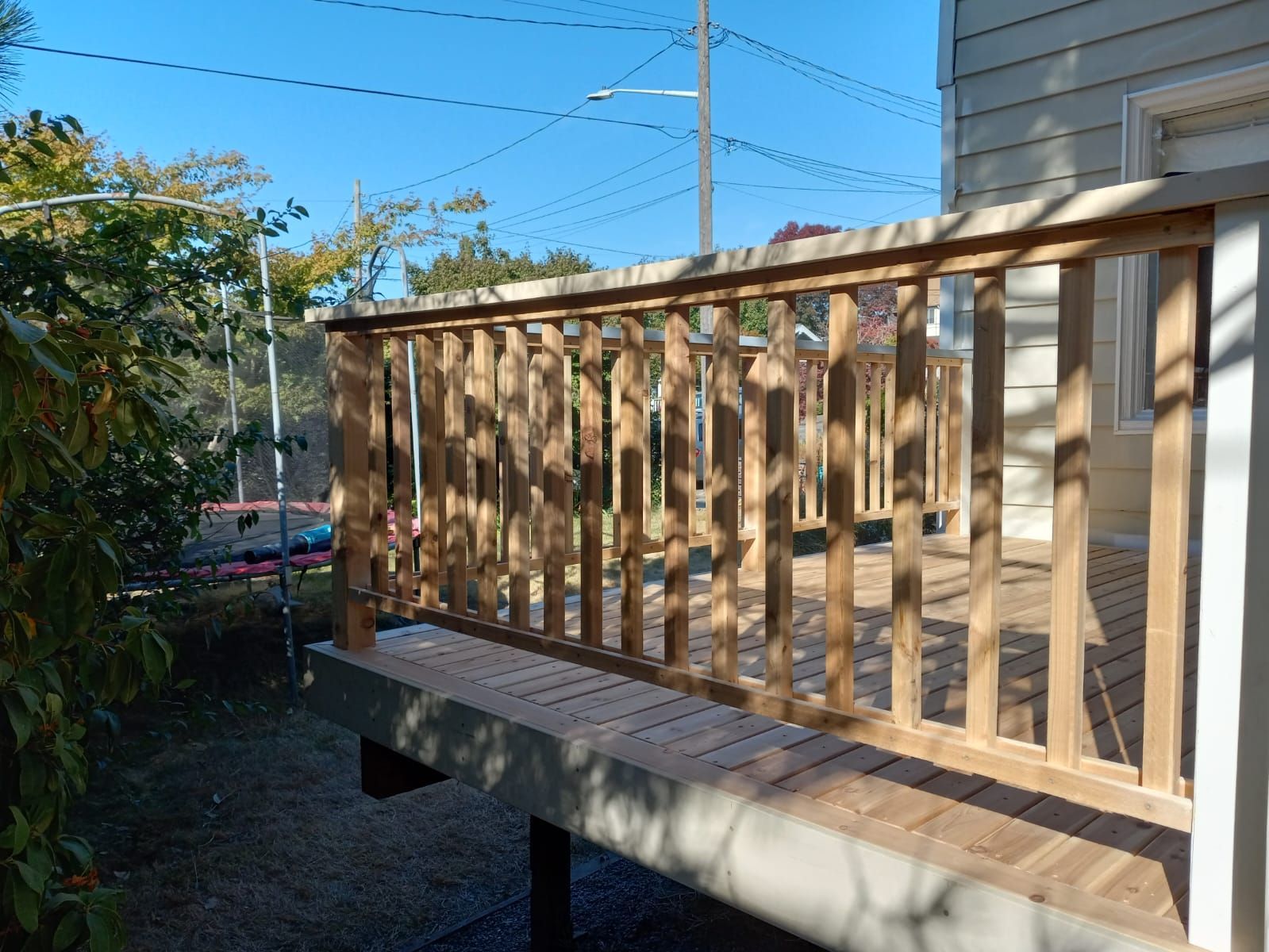 A wooden deck with a railing in front of a house.