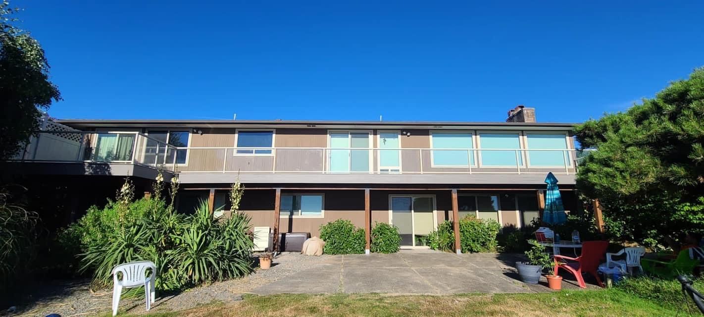 A large house with a lot of windows is sitting on top of a lush green hillside.