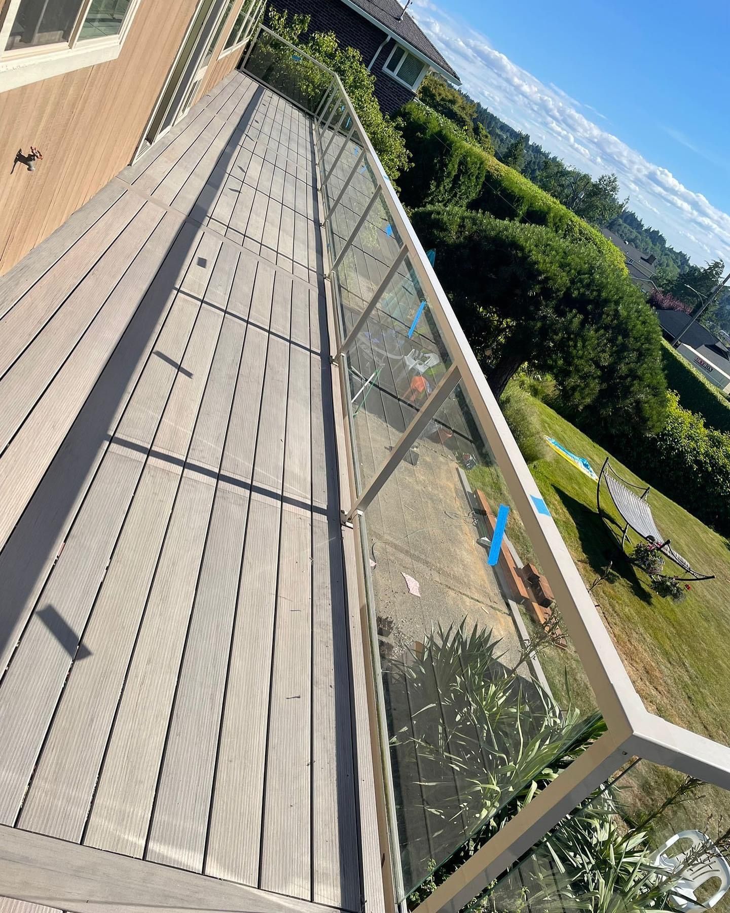 A balcony with a glass railing and a wooden deck