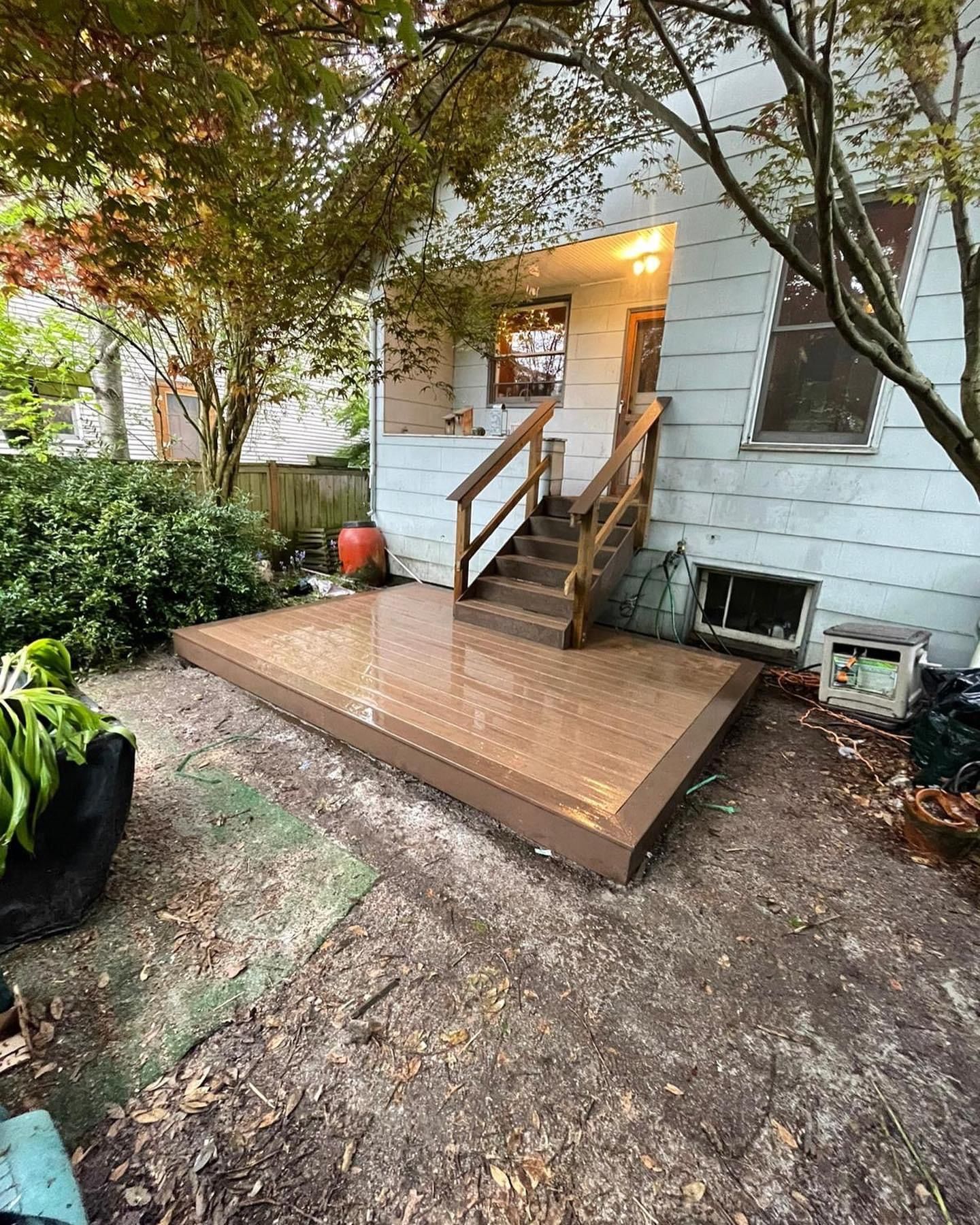 A house with a wooden deck and stairs in the backyard.