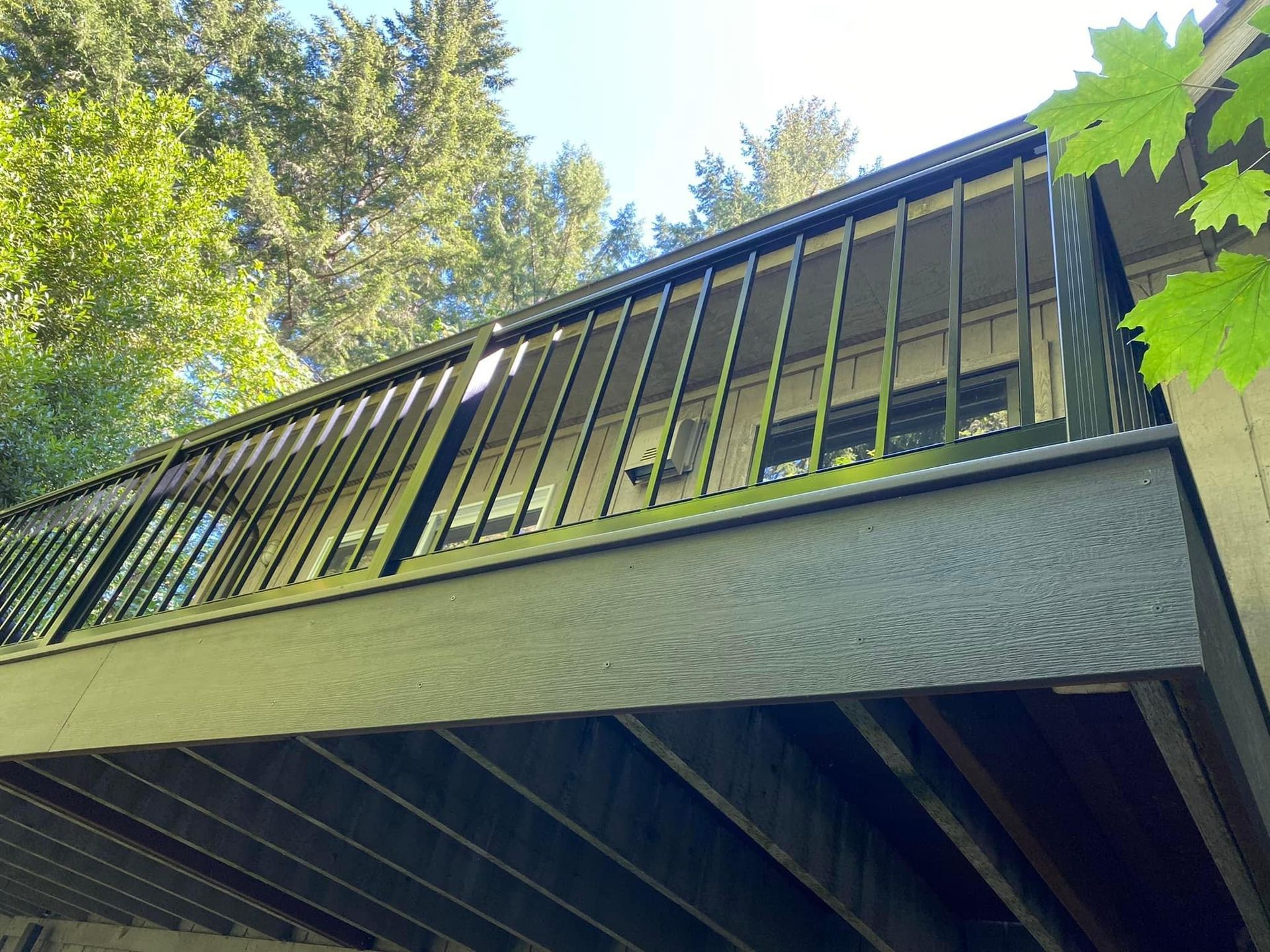 A wooden deck with a metal railing and trees in the background