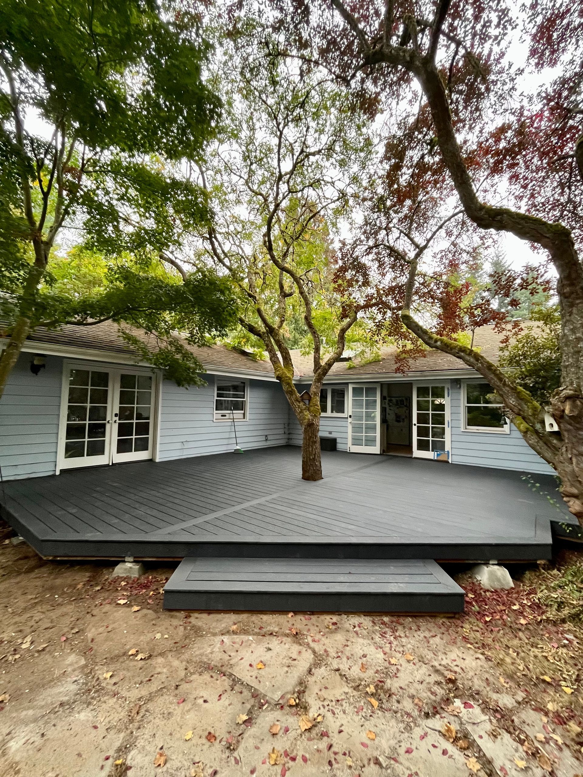A house with a large deck in front of it surrounded by trees.