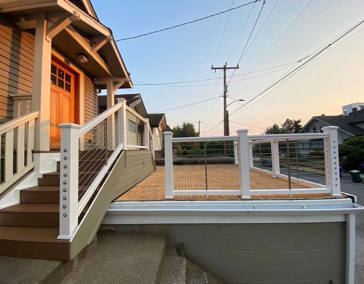 A house with stairs leading up to a deck with a white railing.