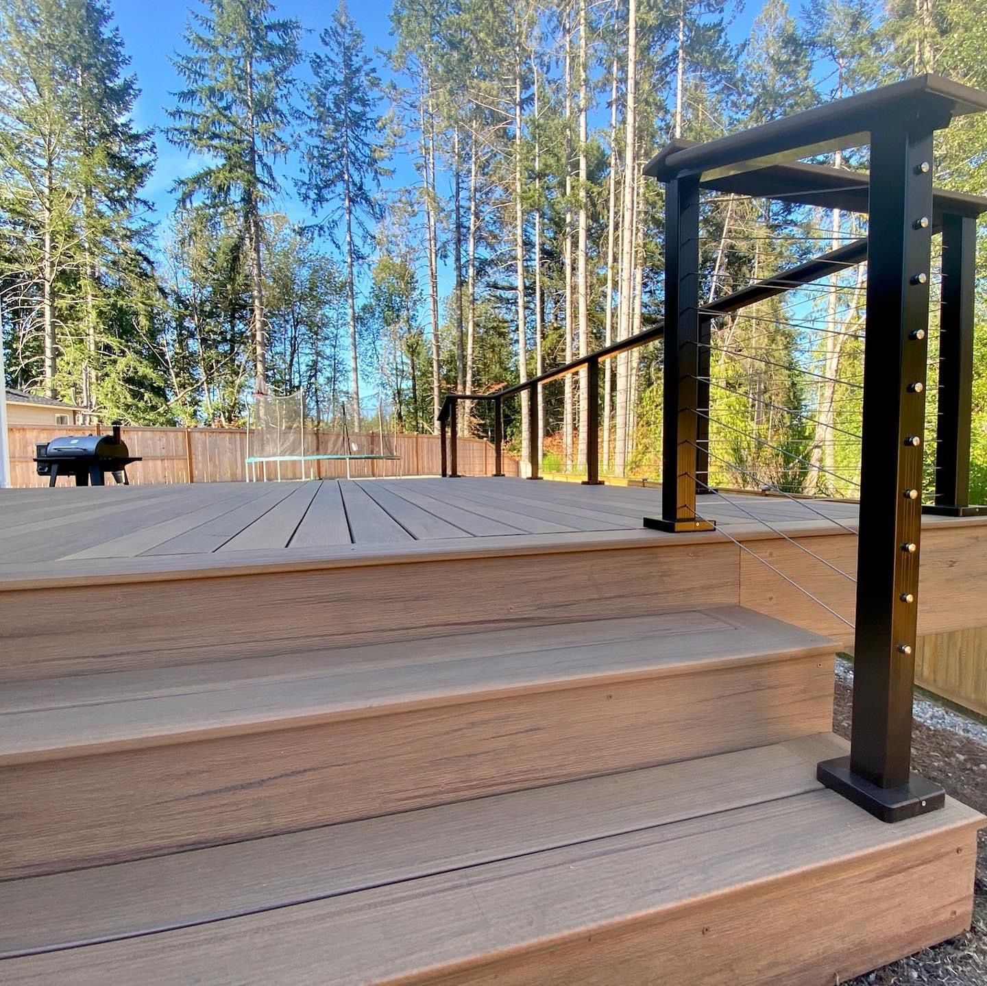 A wooden deck with stairs and a black railing