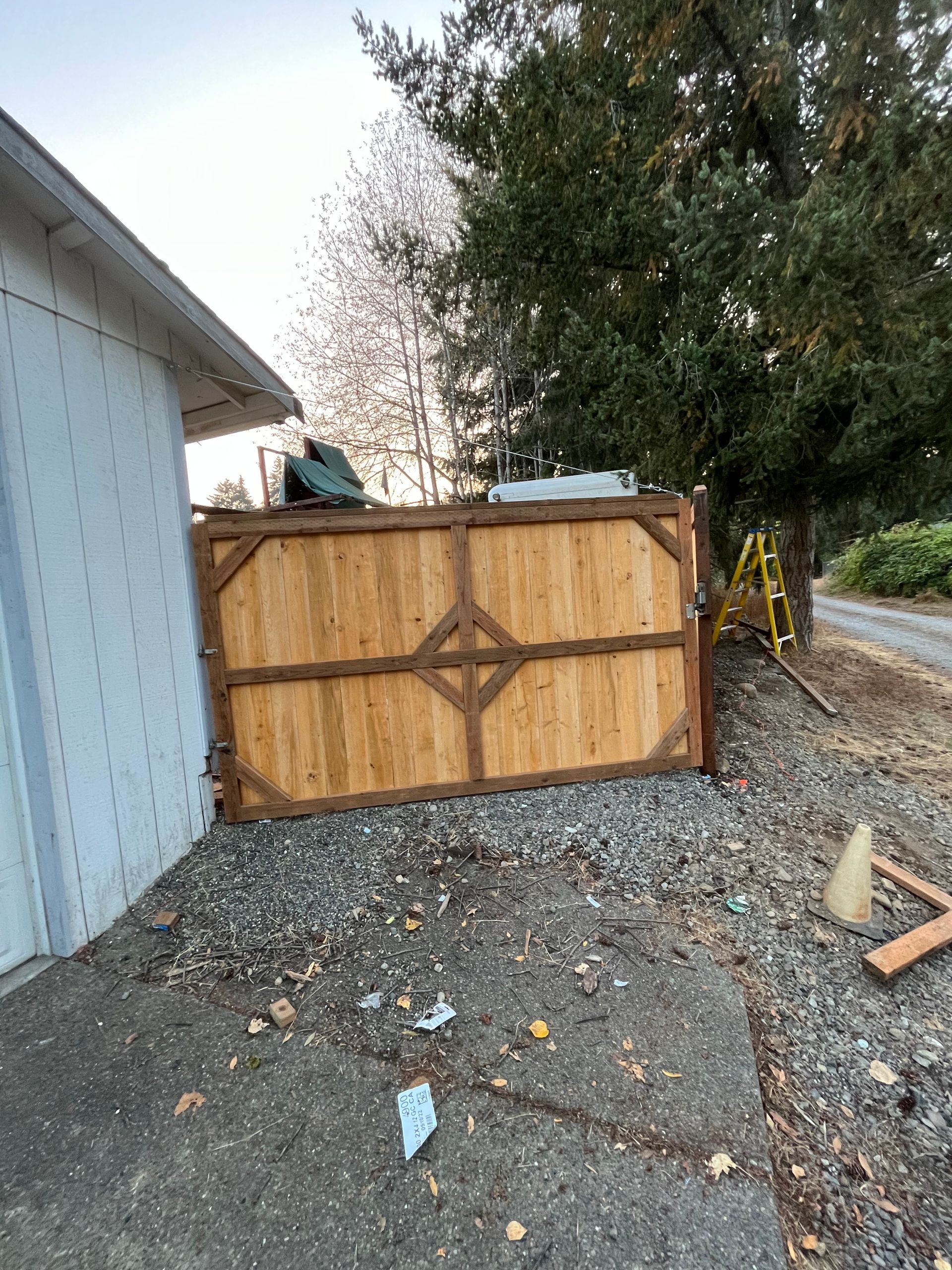 A wooden fence is sitting on the side of the road next to a garage.