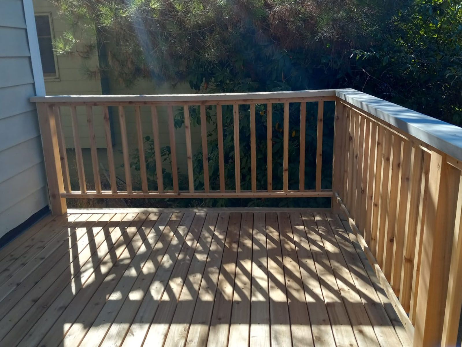 A wooden deck with a railing and trees in the background