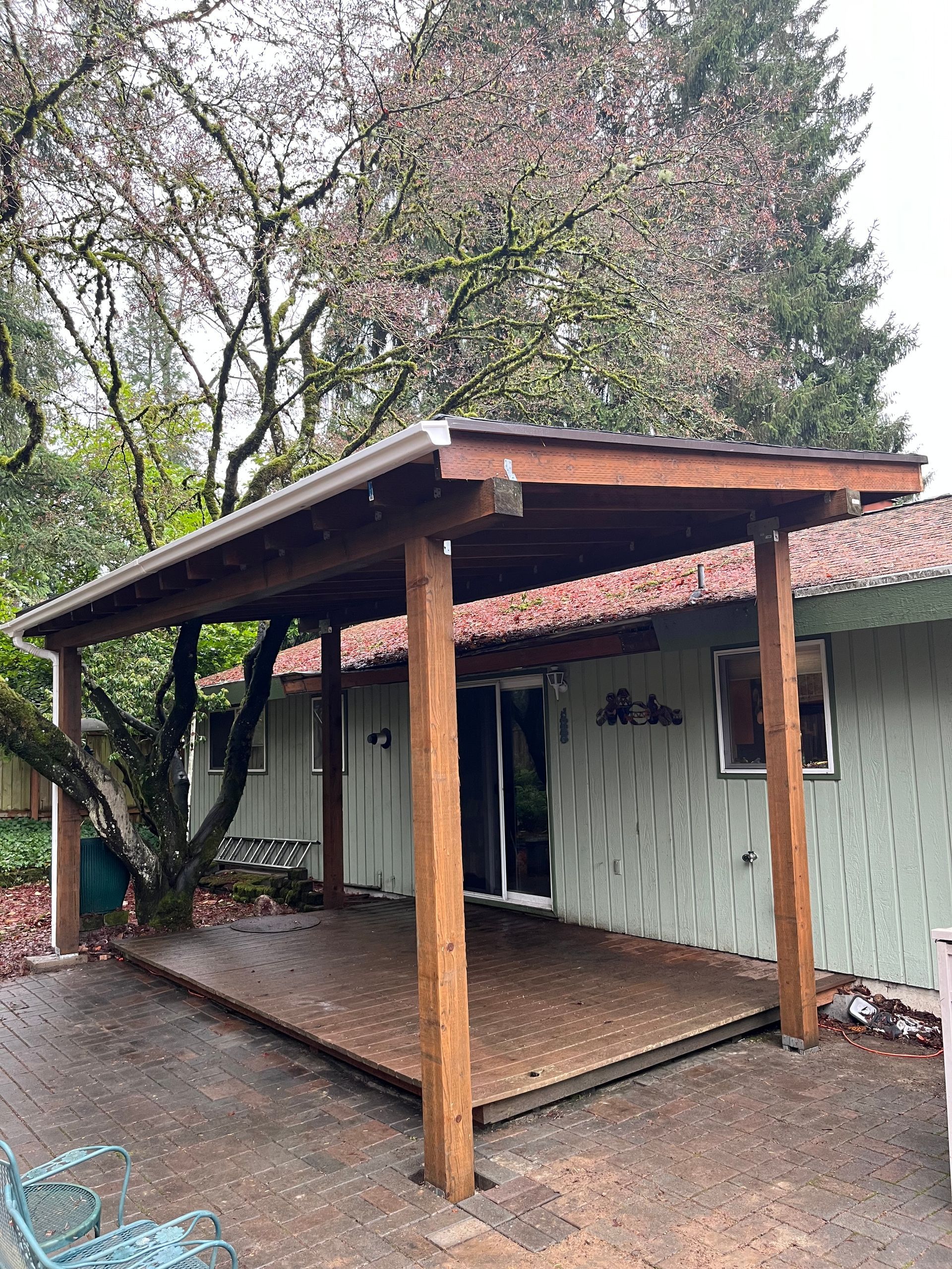 A wooden porch with a roof over it is in front of a house.