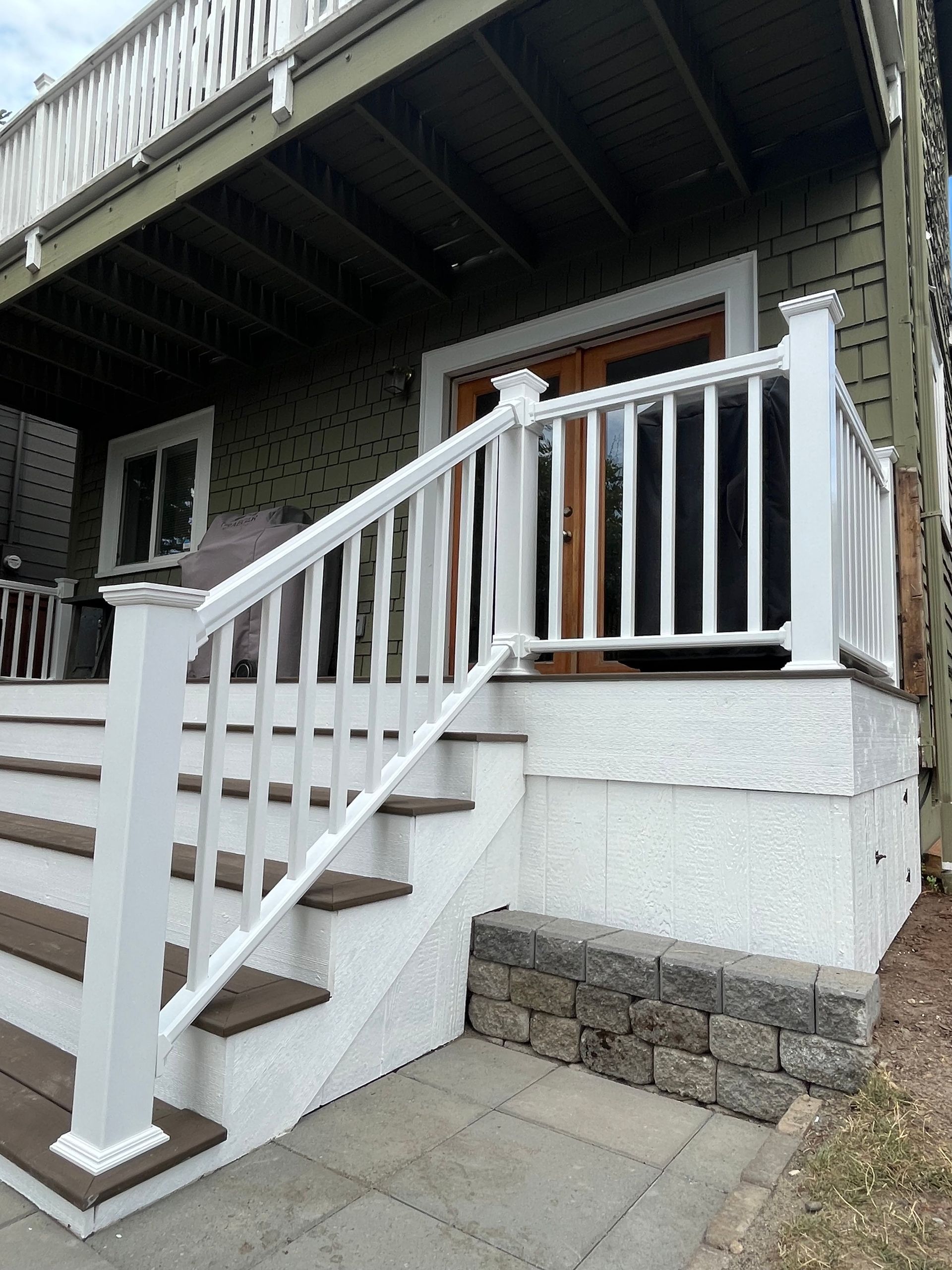 A white railing is on the front porch of a house.