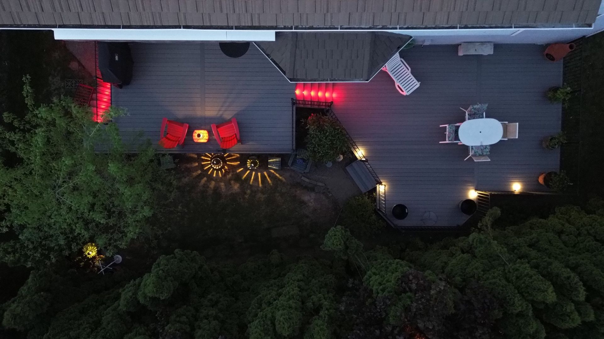 An aerial view of a deck with a table and chairs at night.