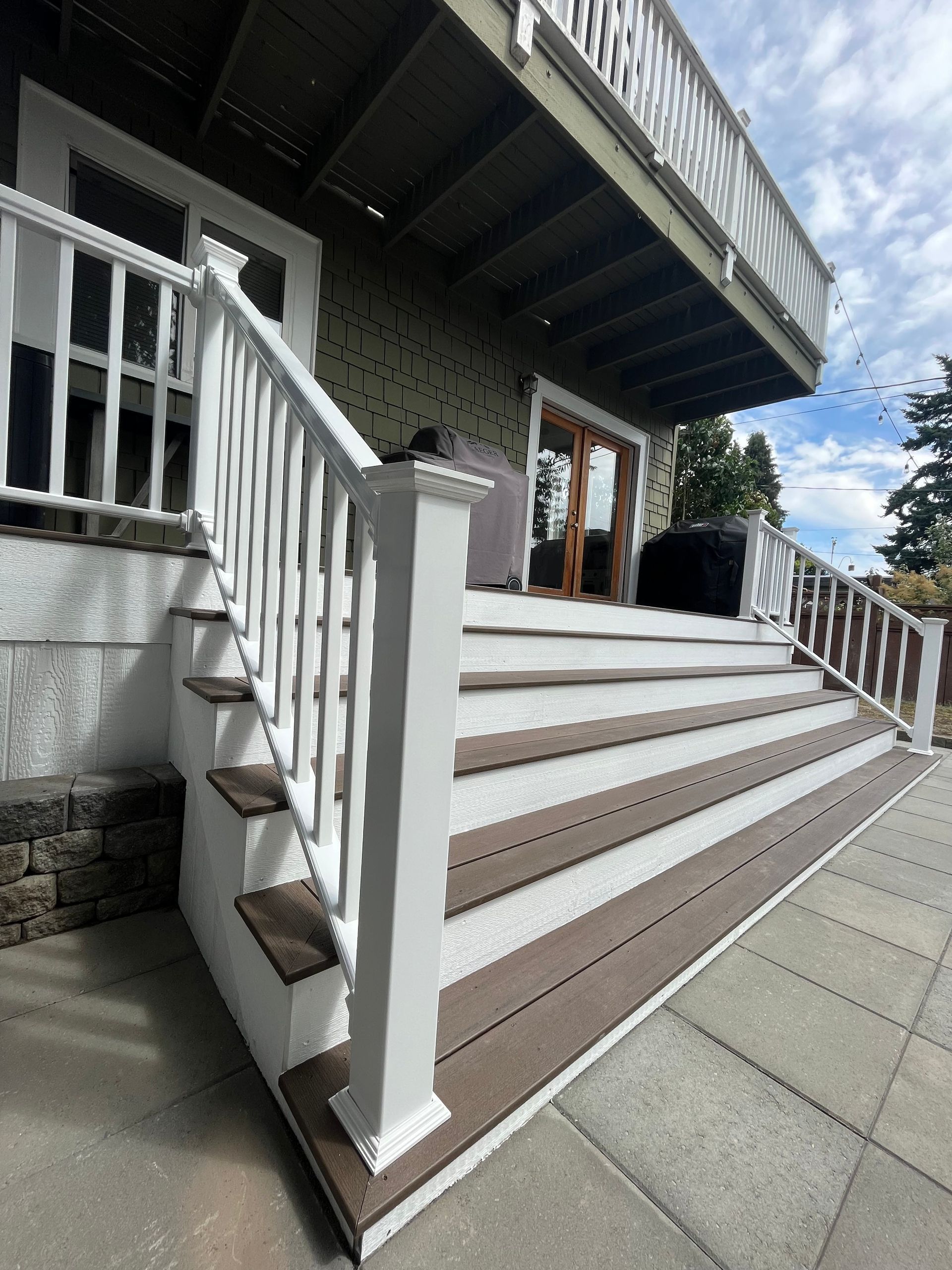 A deck with stairs leading up to it and a white railing.