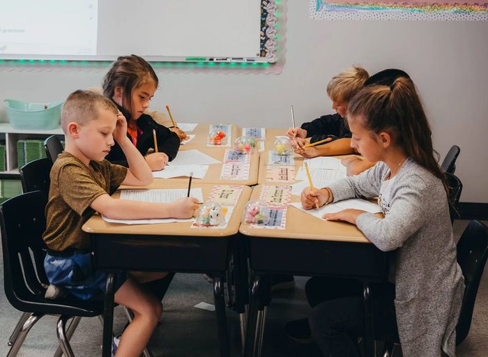 Children writing at desks in a classroom.